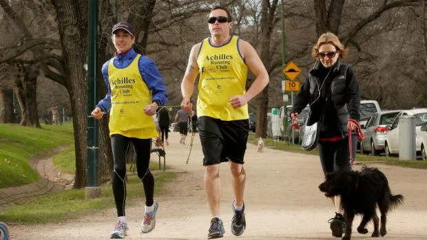 Adam with his guide Amelia Griffith, running around The Tan track in Melbourne
