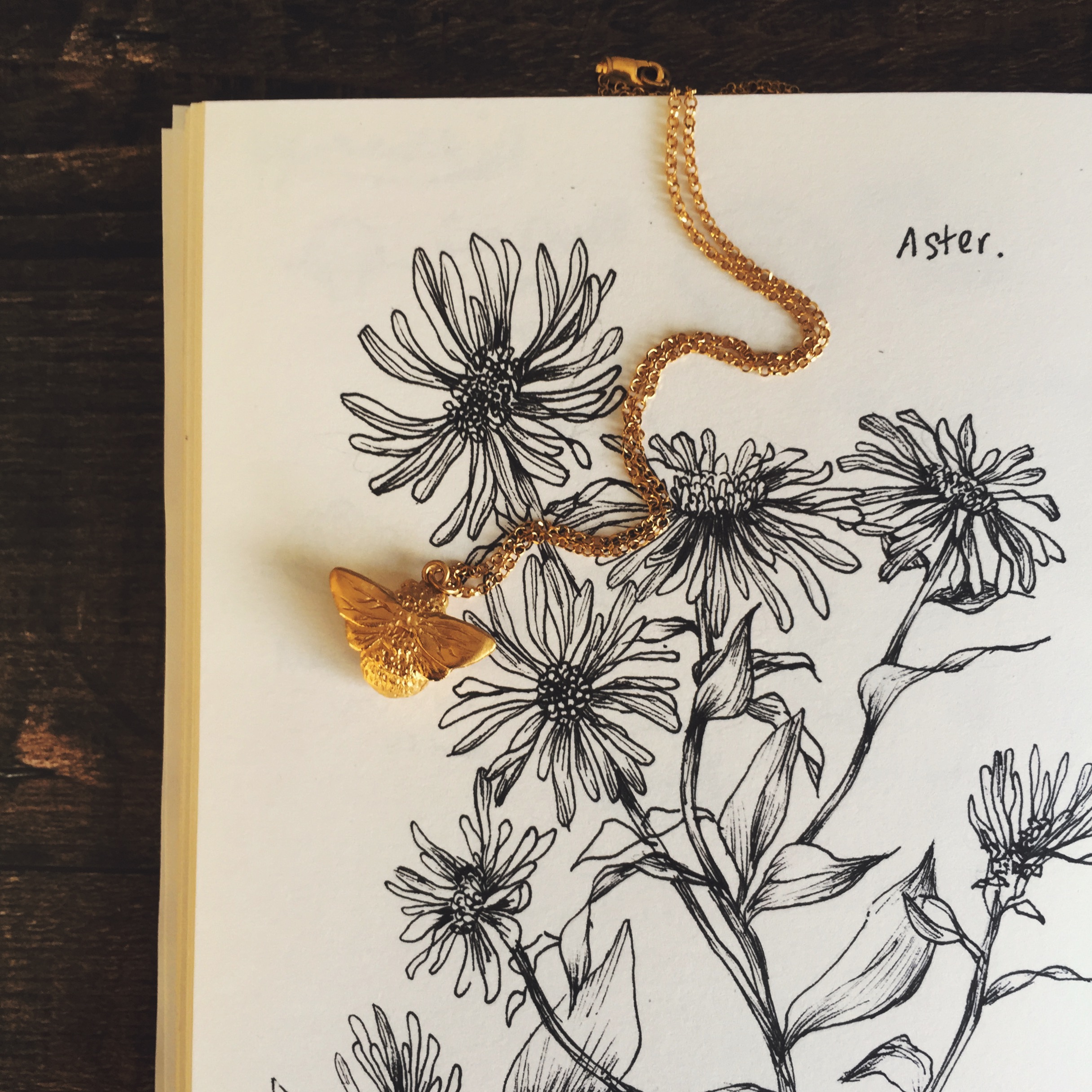 Our buzzy bumblebee necklace against a little sketch of wildflowers.
