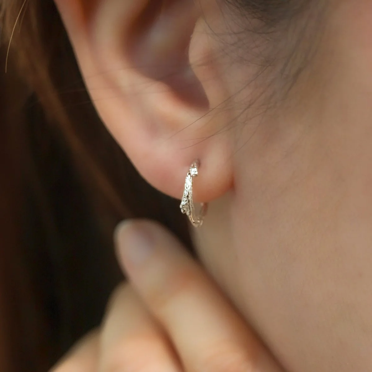 silver twig hoop earring close up on ear