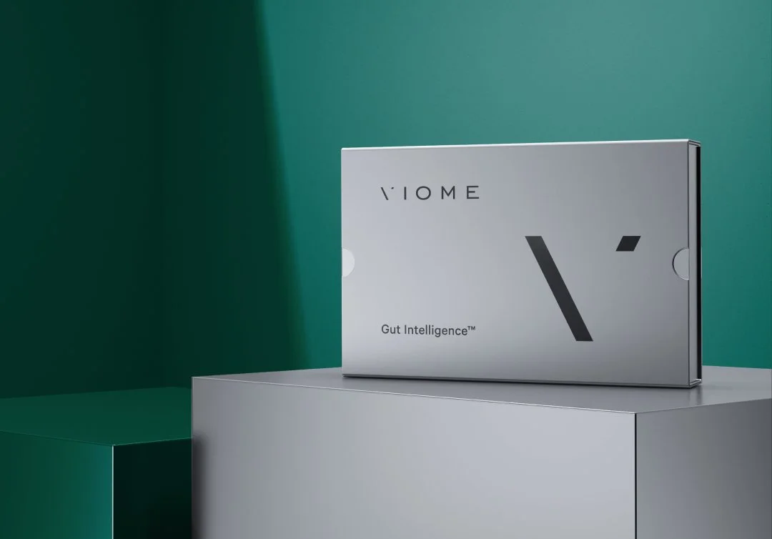 A box labeled 'V IOME Gut Intelligence' on a silver pedestal, with a minimalistic design and modern background.