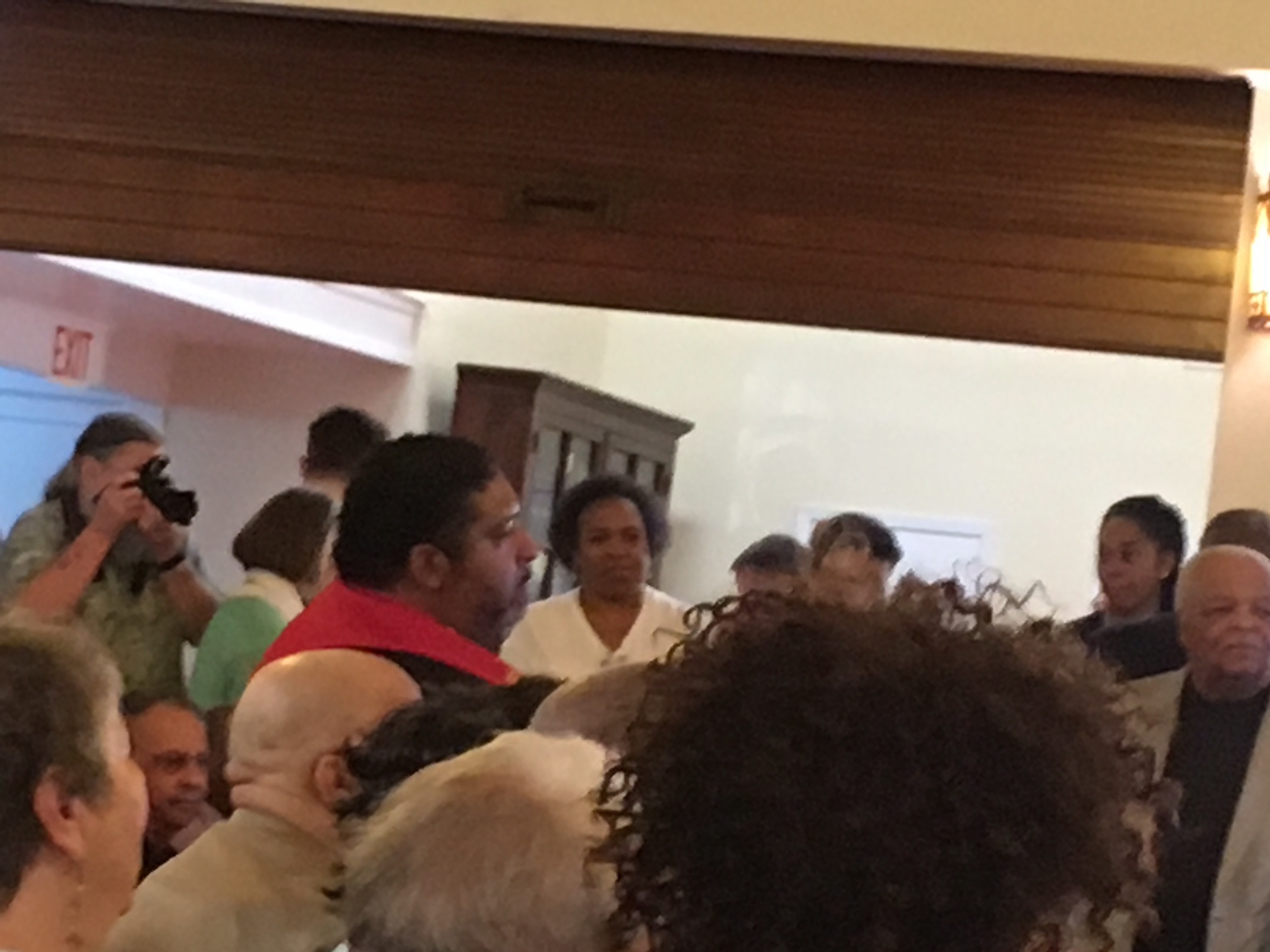 Reverend Barber on a stool taking in the words of affirmation and blessings being spoken