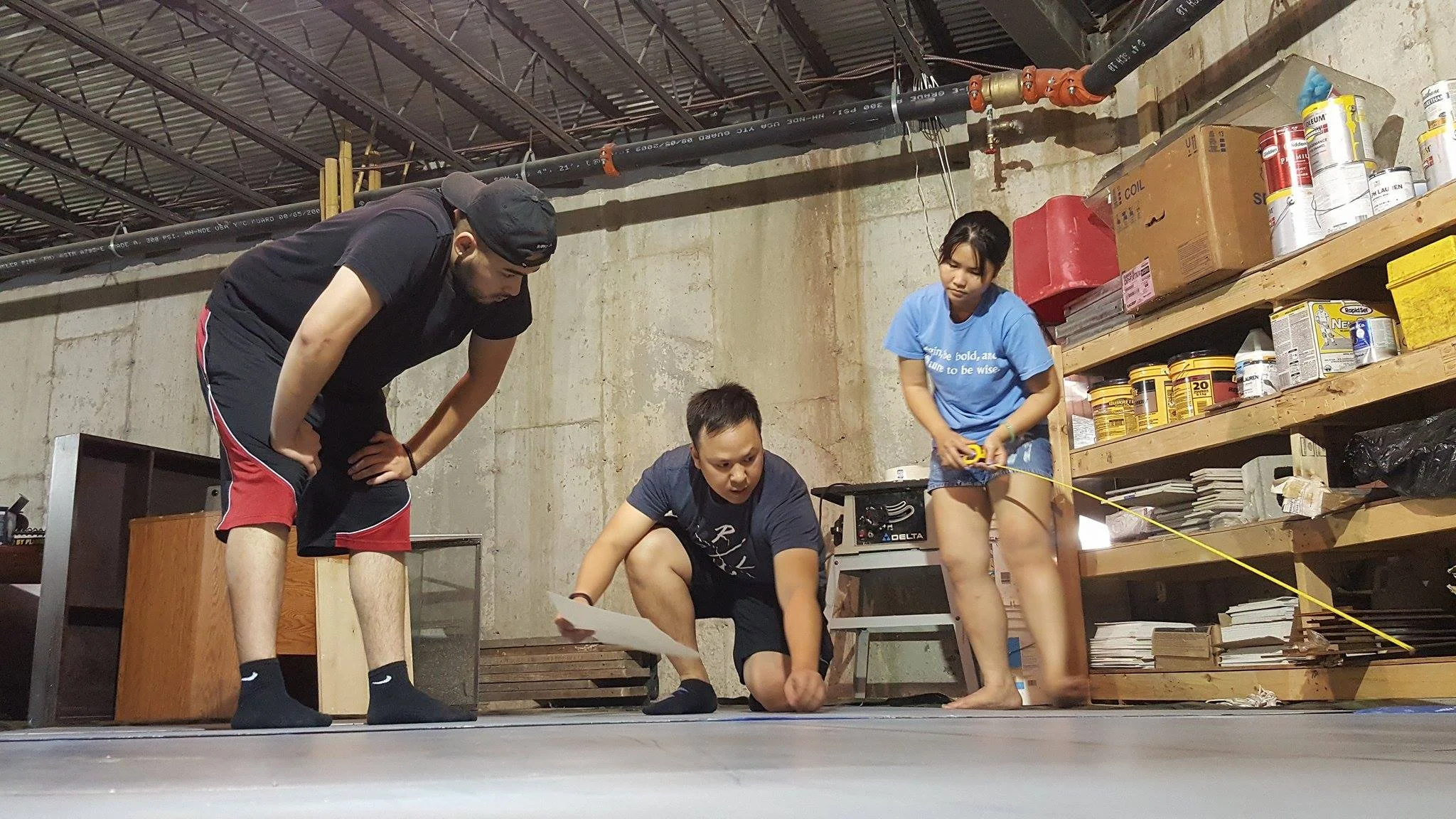 Left to Right: Tony, Tam, and Tran. Photo Credit: Kathy Le Art team discussing about where each picture is placed with measurements.