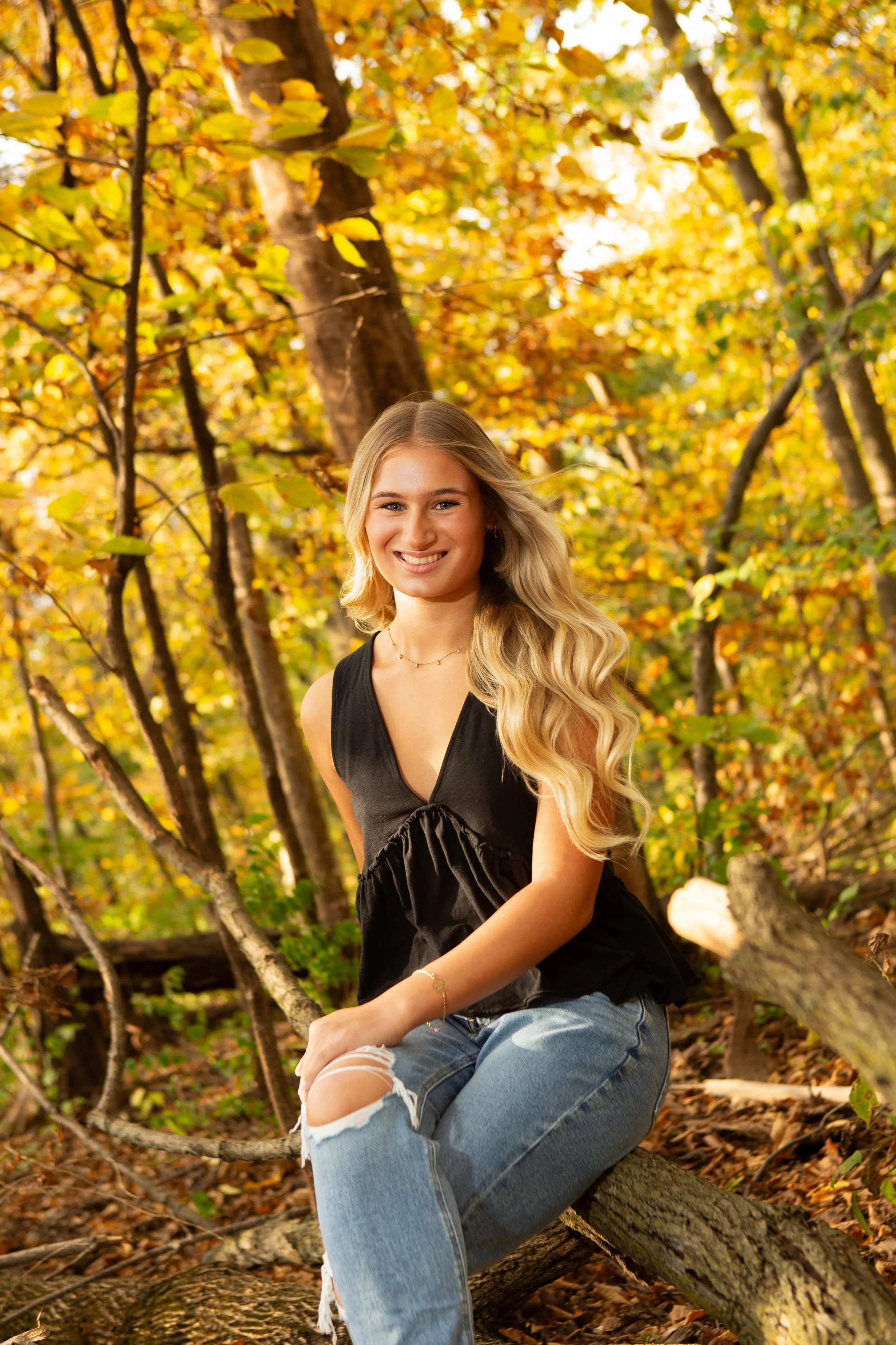Senior Girl black top with fall leaves surrounding her