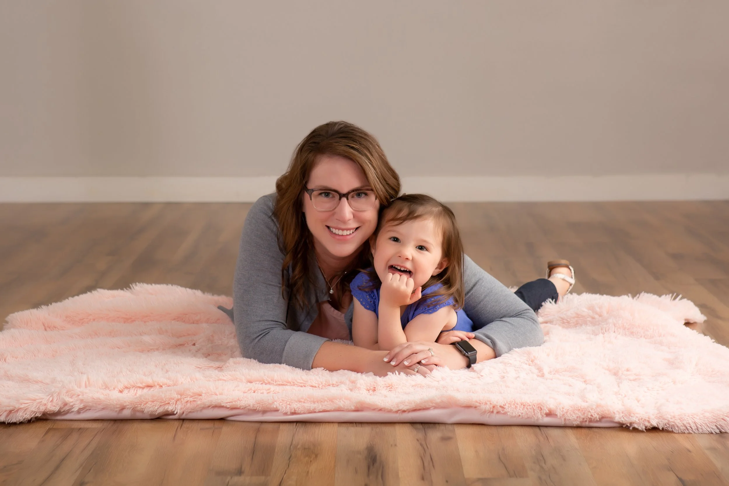 A Mom and her Daughter laying on the floor laughing during an Adalily Session