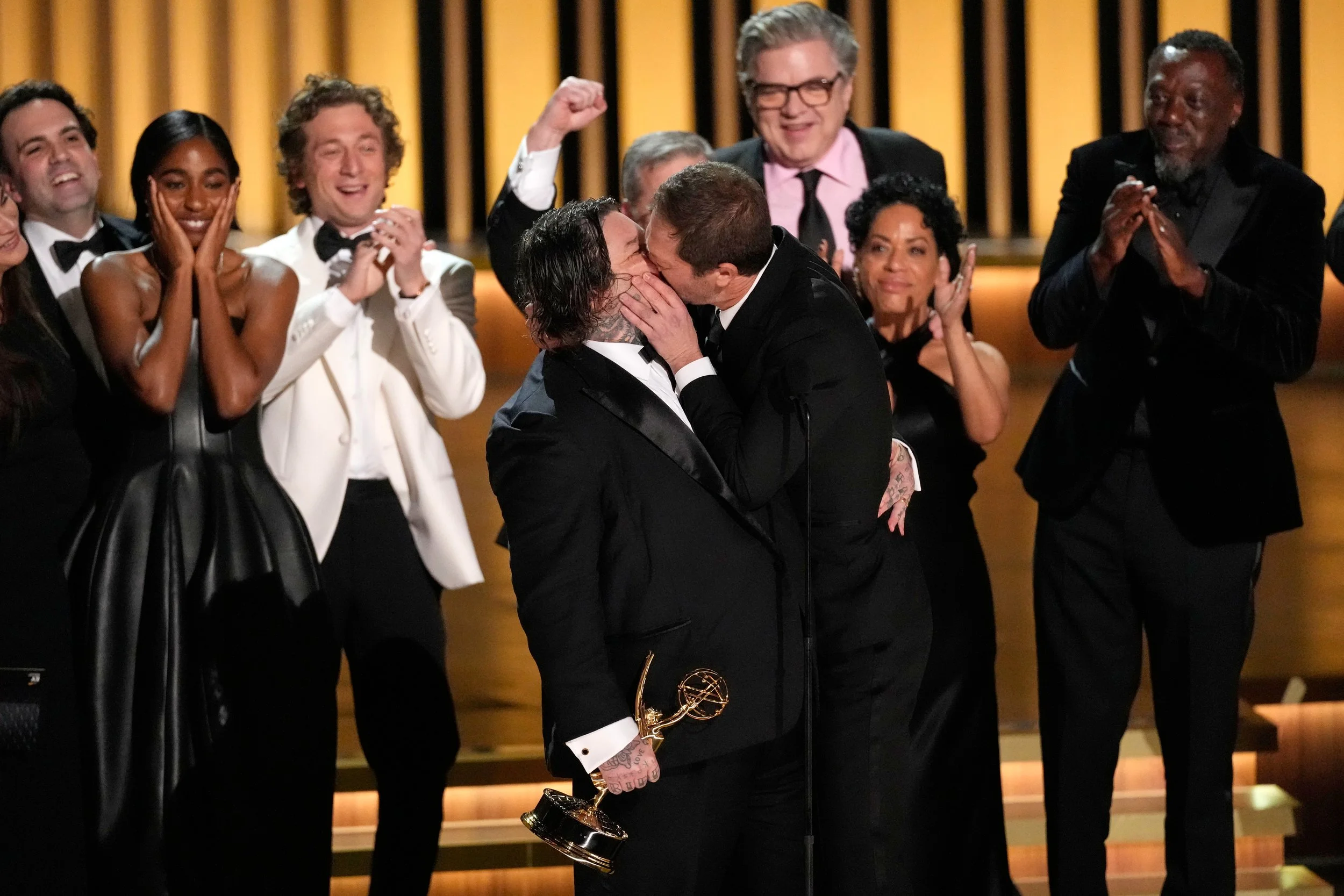  Matty Matheson, center, and Ebon Moss-Bachrach kiss as "The Bear" wins the award for outstanding comedy series during the 75th Primetime Emmy Awards on Monday, Jan. 15, 2024, at the Peacock Theater in Los Angeles. (AP Photo/Chris Pizzello) 