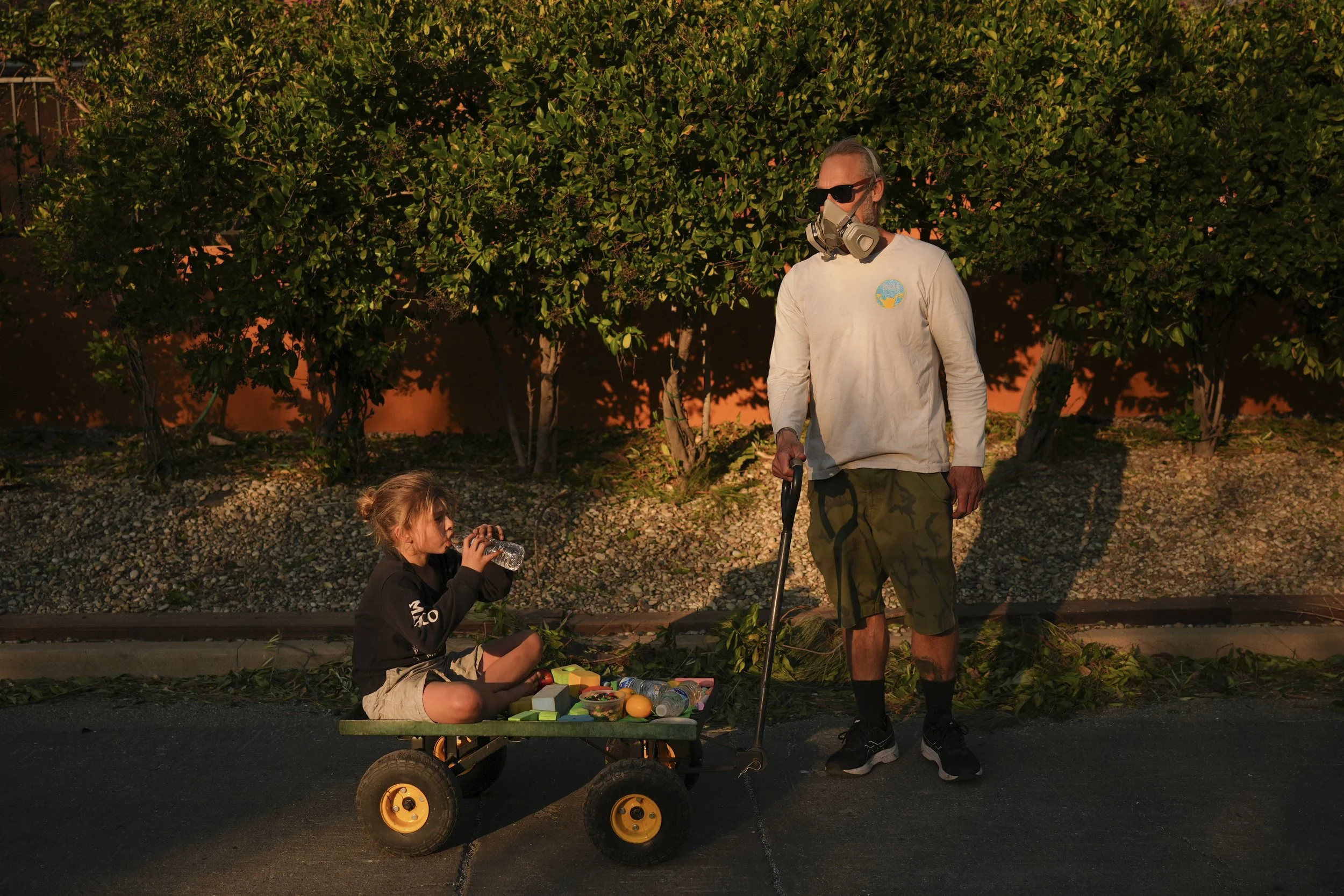  Resident Pauly Harter, right, pulls his son Gavin on a cart during a walk Friday, Jan. 10, 2025, in Altadena, Calif. (AP Photo/Jae C. Hong) 