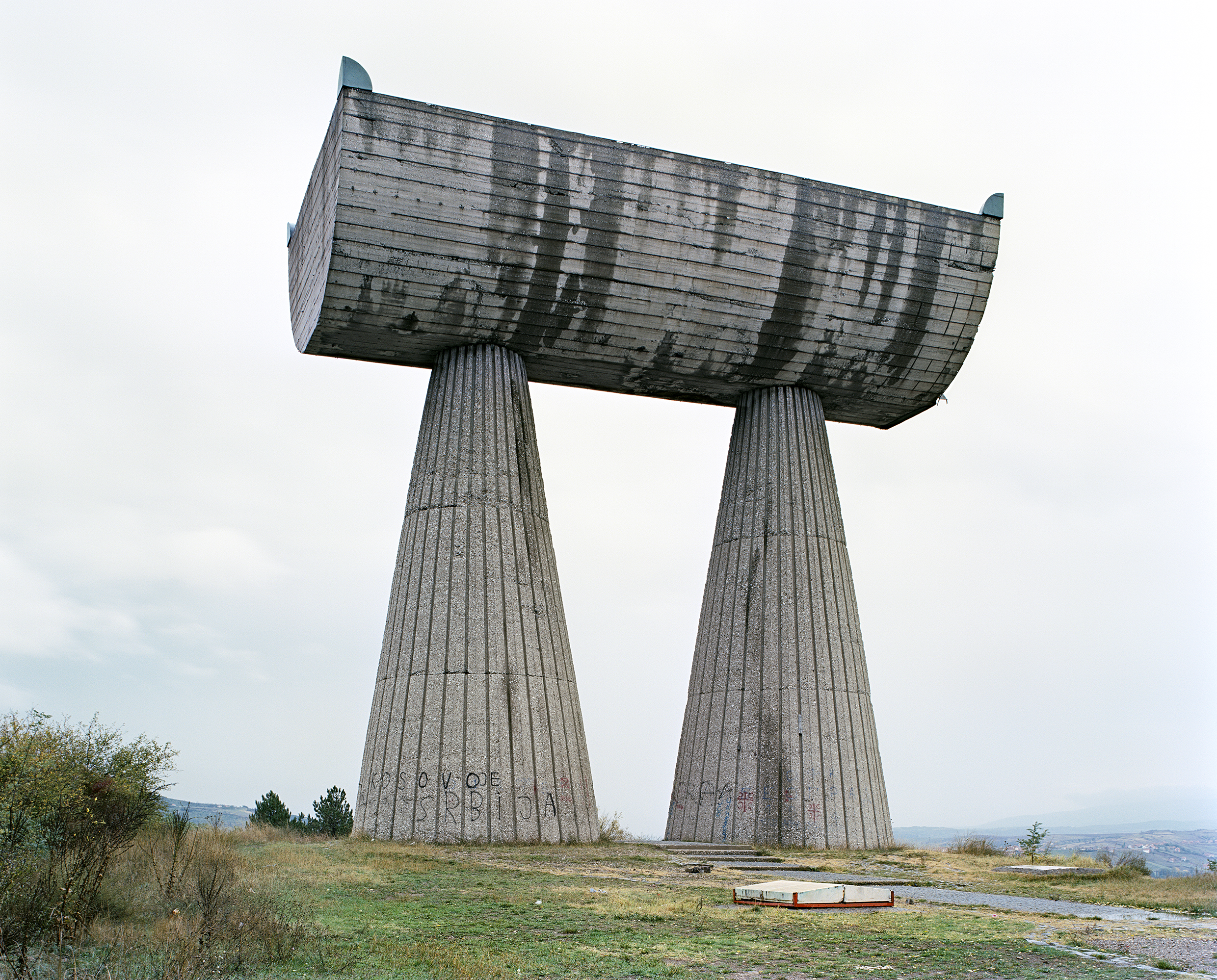 Jan Kempenaers, Mitrovića from his 2010 publication 'Spomenik'. Standing in the form of some lost Roman addition to Stonehenge, Bogdanović's huge concrete monument in the town of Mitrovica is a homage to those who were lost during fighting in World War II.