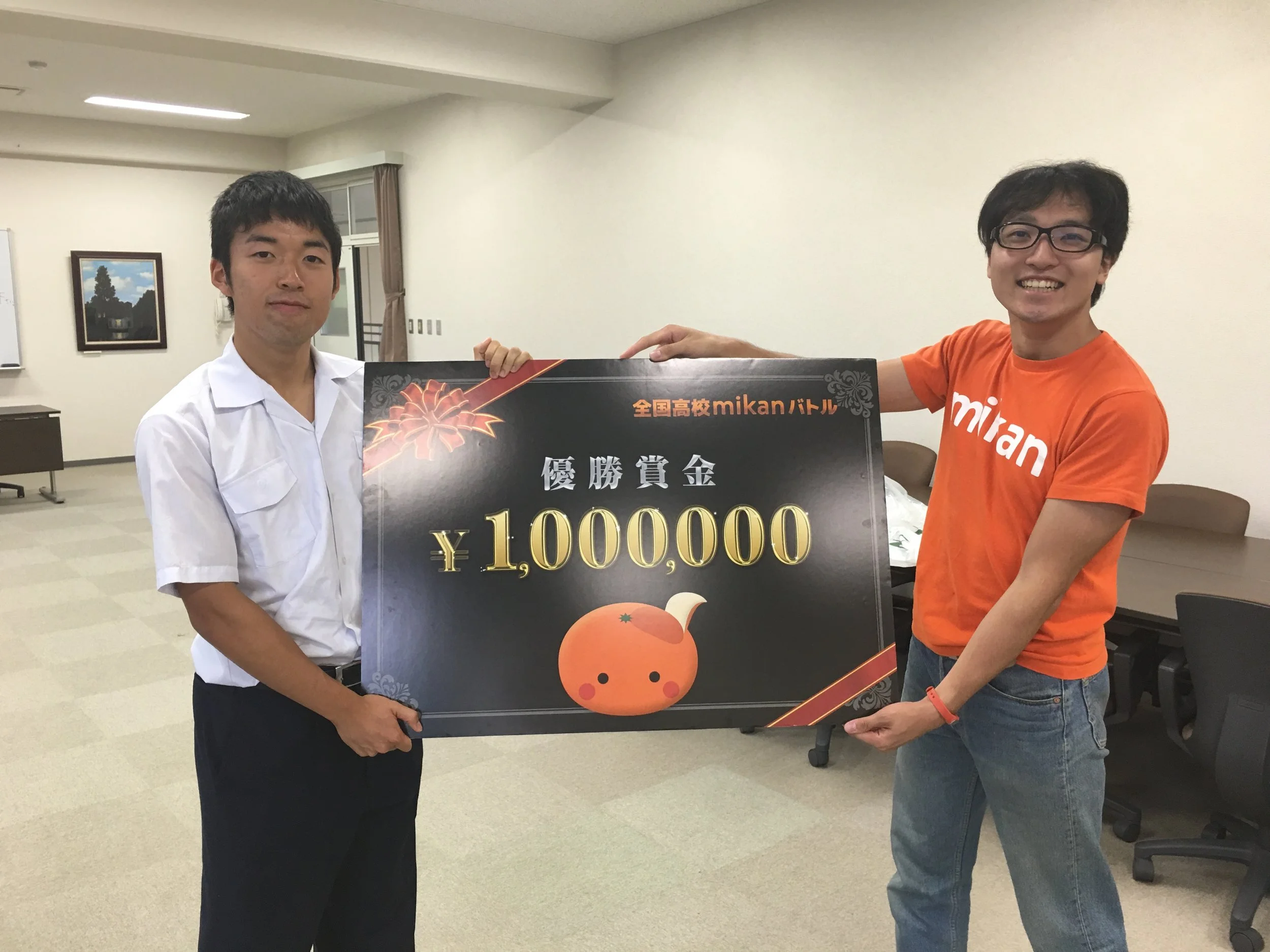 暁高校のmikan大使として活躍した利太郎君。代表の宇佐美から、mikan特製の優勝賞金100万円のボードを贈呈しました。