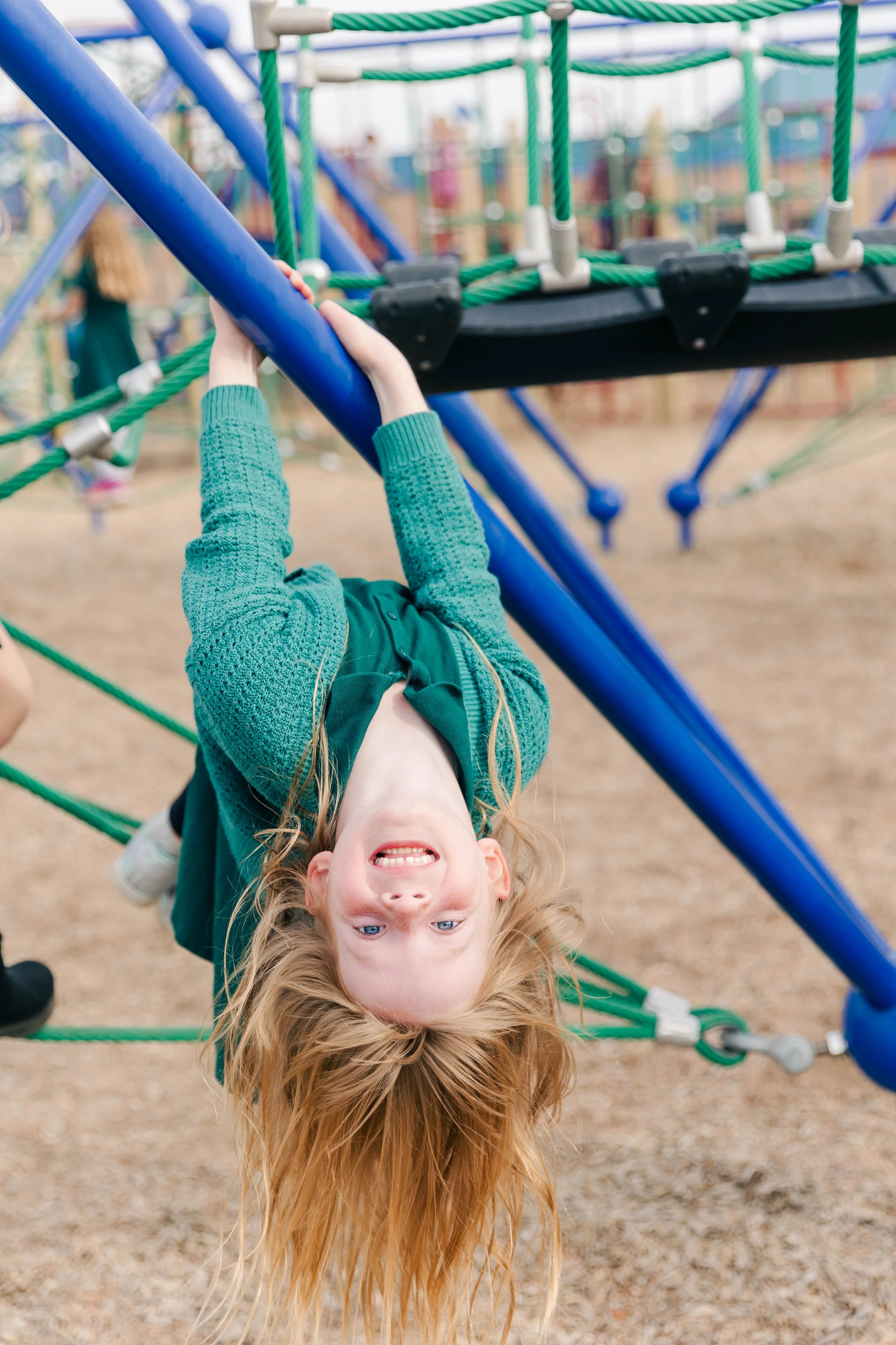Student hanging upside down on the jungle gym