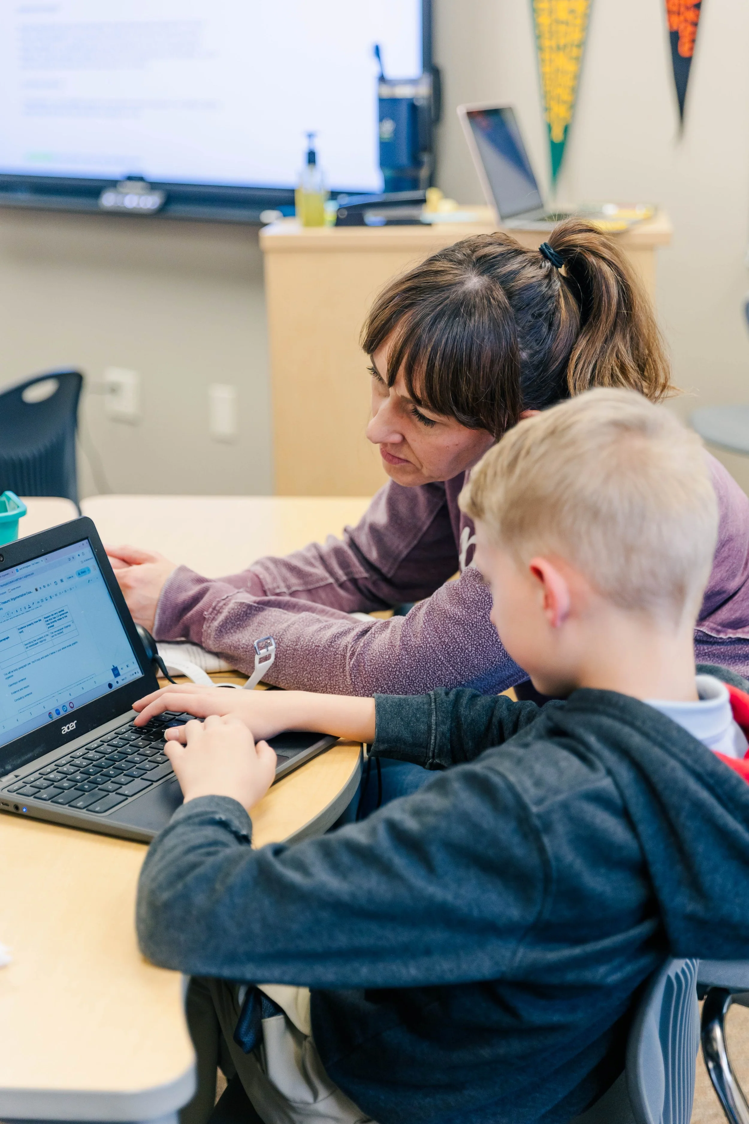 Teacher working with a student on a laptop