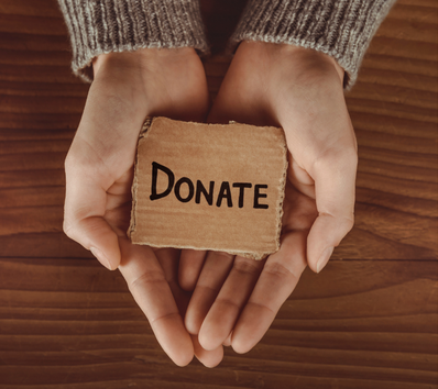 A person holding a small cardboard sign that says donate