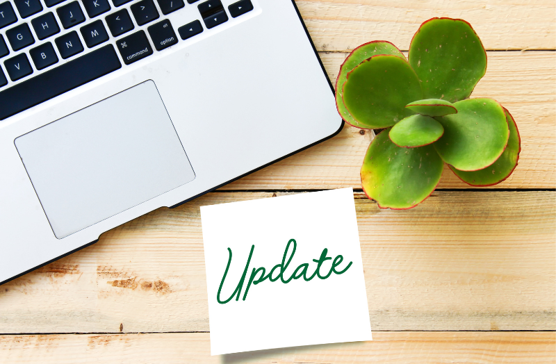 Laptop on a wooden desk, with a small succulent plant, and a note that says "update"