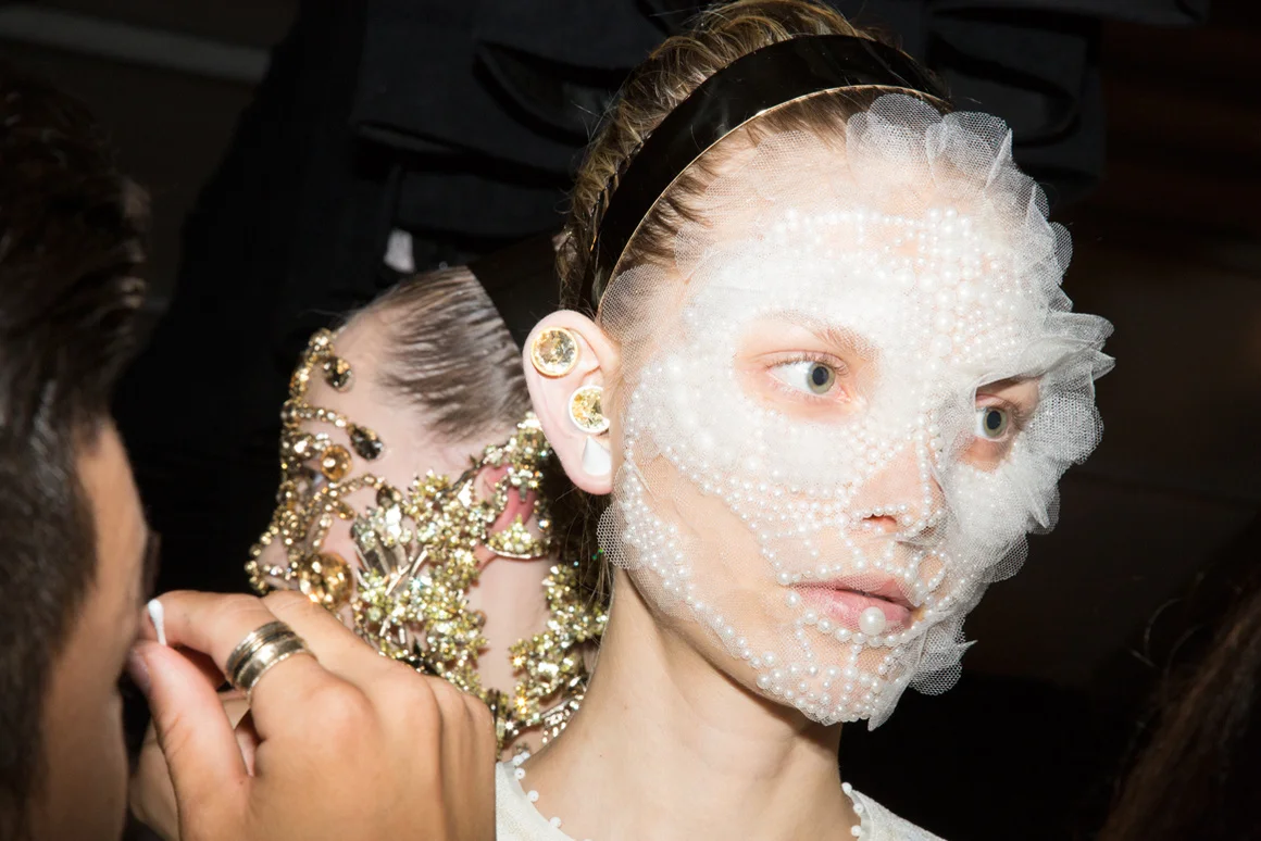 Backstage, the finishing touches are applied in hair and makeup; image via