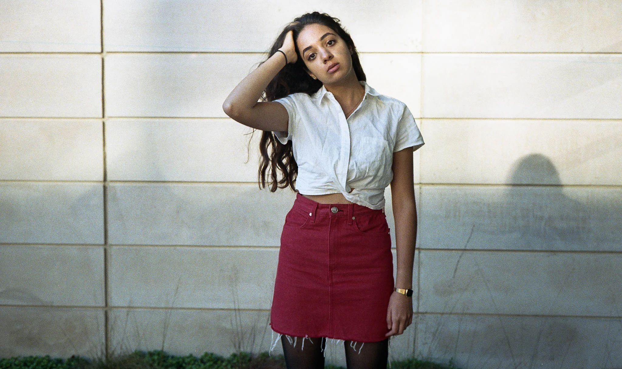 The cropped white button-down is from Free People, red skirt from Rag and Bone. The suede, brown, knee-high boots are from Urban Outfitters. The accessories are a hamsa (evil eye) necklace, tiny gold hoop earrings, gold casio watch