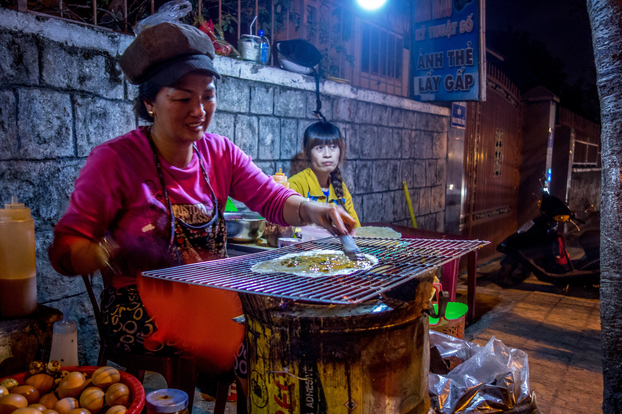 A woman making banh trang nuong on the street in Da Lat. 