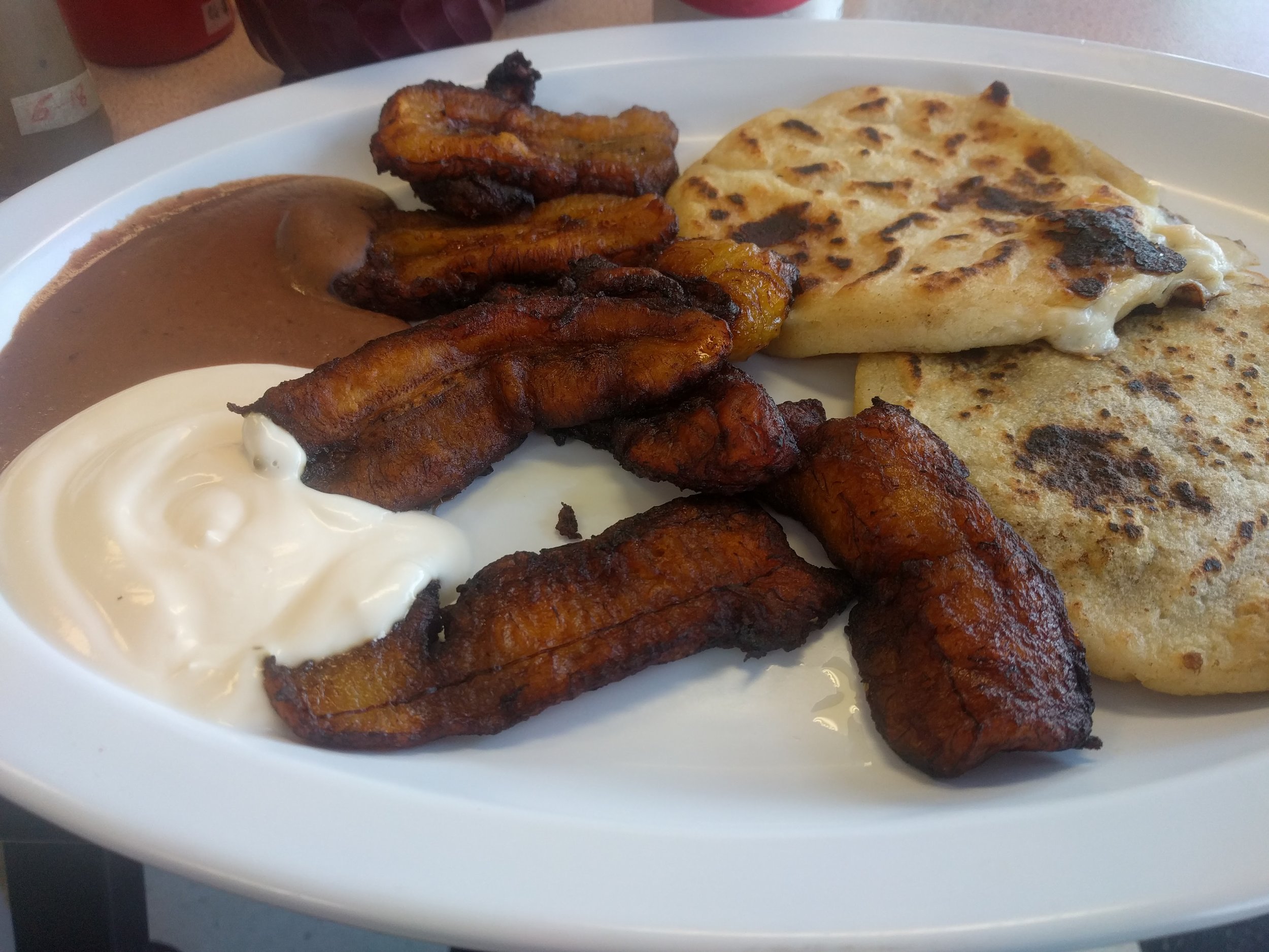 Pupusas with fried plantains, refried beans, and crema. 