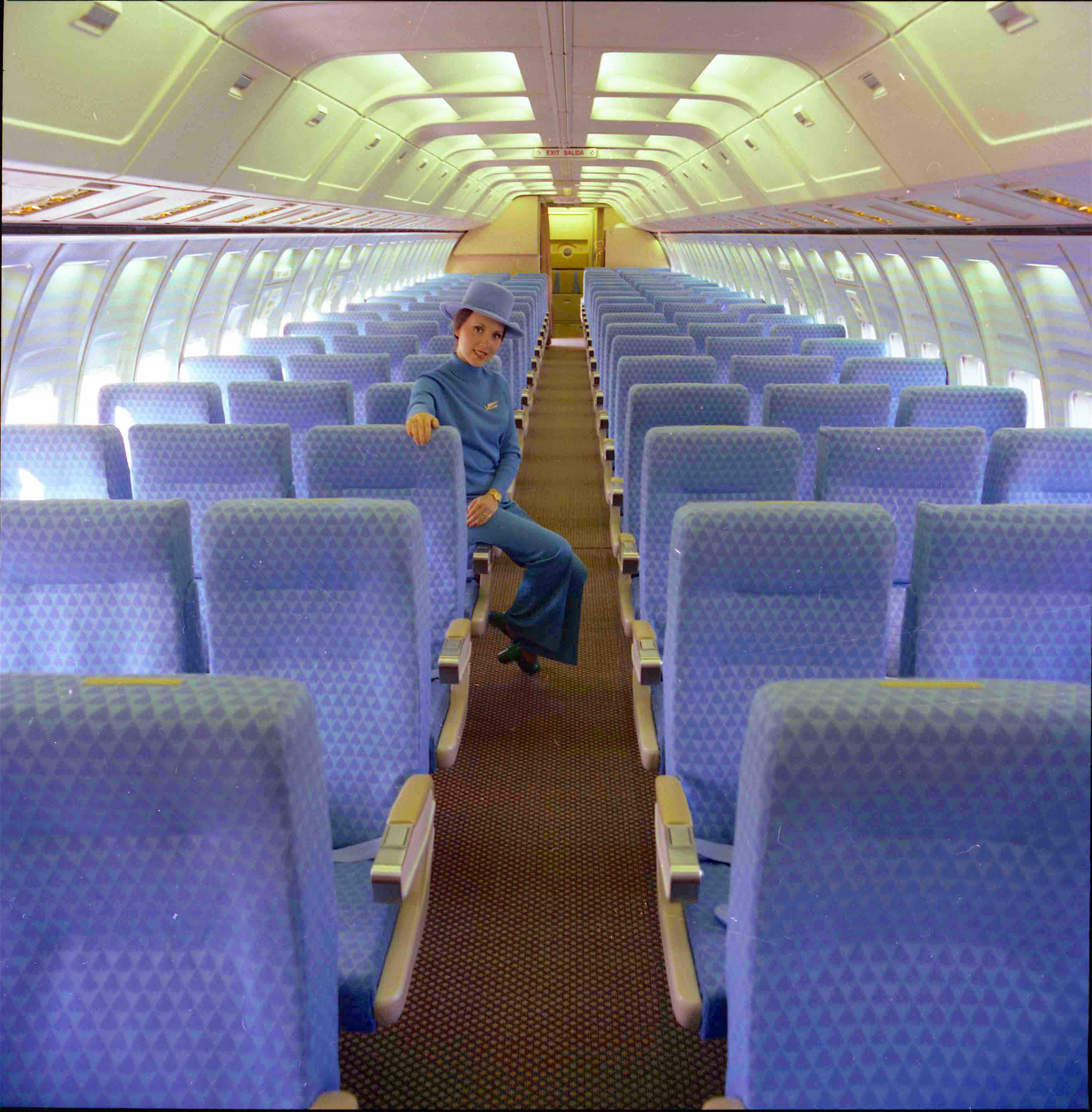The Sumptuous Arrowhead Blue Coach Class Boeing 727 Interior with Hostess Modeling 1974 Emilio Pucci Classic Collection Uniform