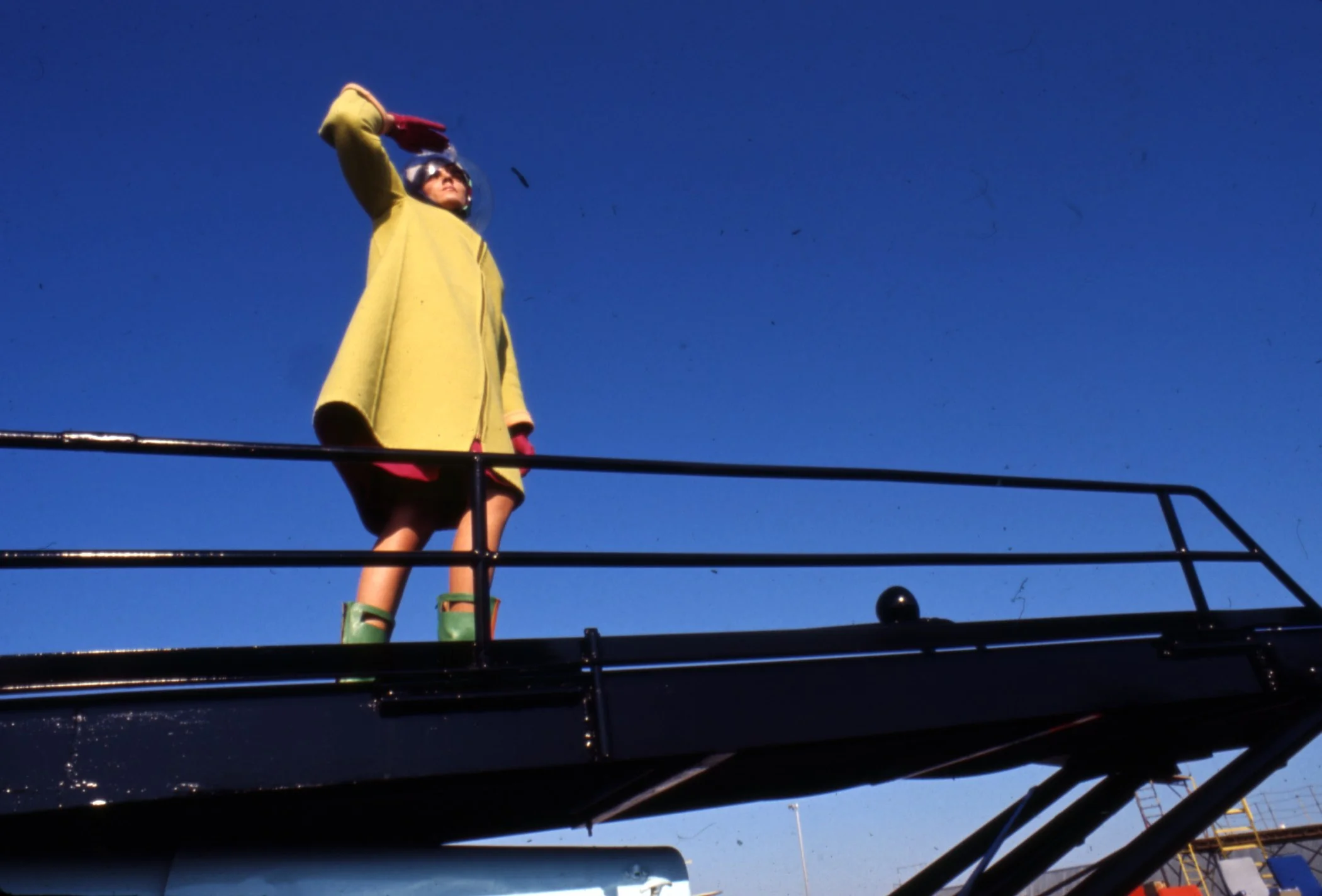 A Braniff Hostess is Modeling the 1965 Emilio Pucci Gemini IV Collection Uniform with Apricot/Absinthe Reversible Wool Coat, Beth Levine Leather Boots and RainDome Space Helmet