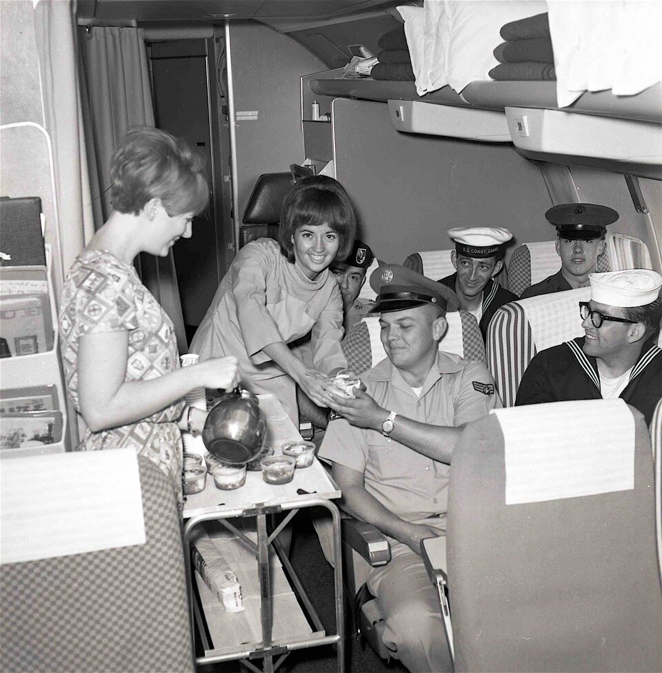 Braniff Hostesses serving weary Vietnam soldiers traveling back home for break in 1966