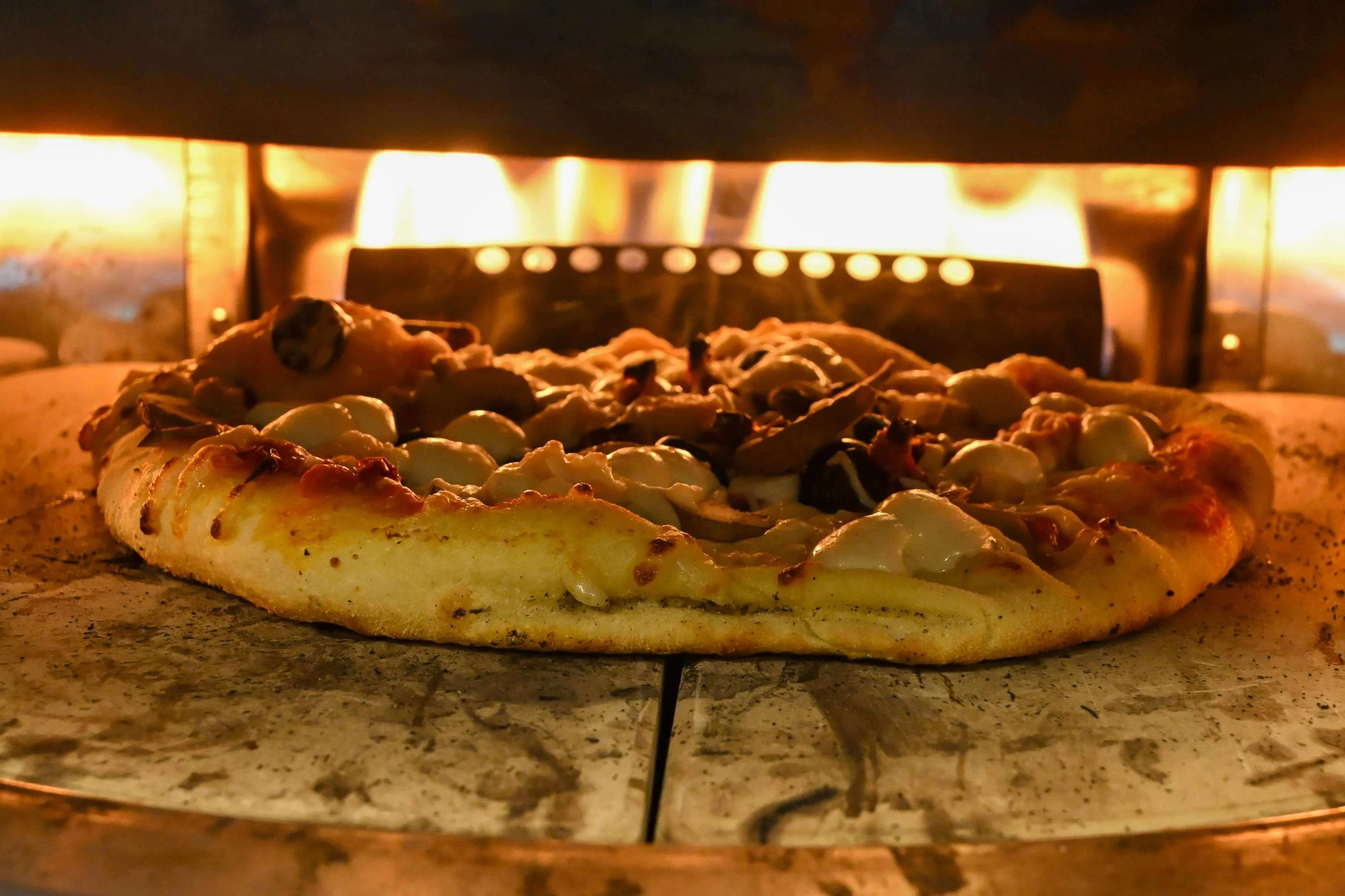 Wood-fired Neapolitan pizza cooking in a traditional oven at Pizza Barbone in Cape Cod
