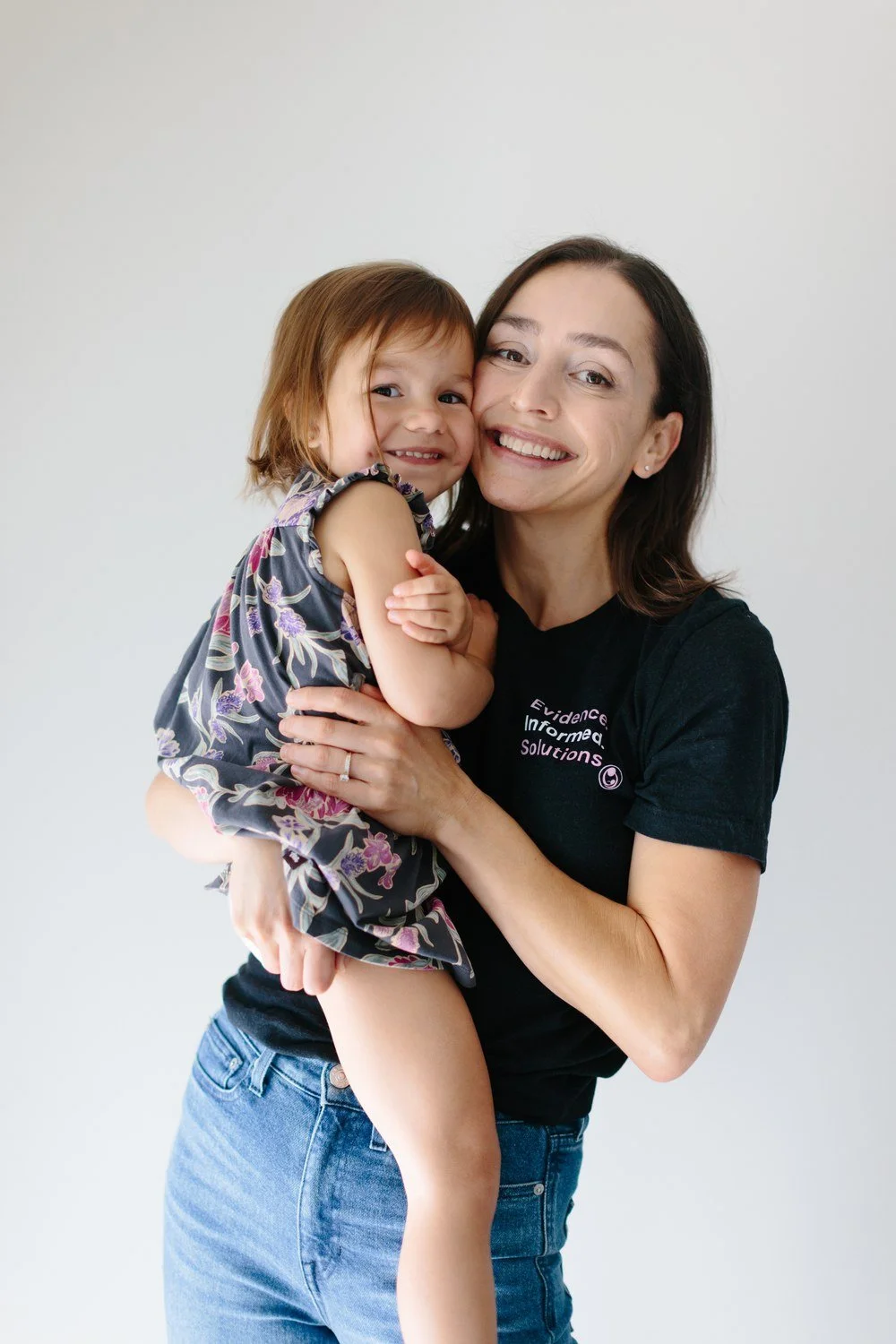 Jamie Mueller holding a smiling child against her shoulder, both facing the camera.