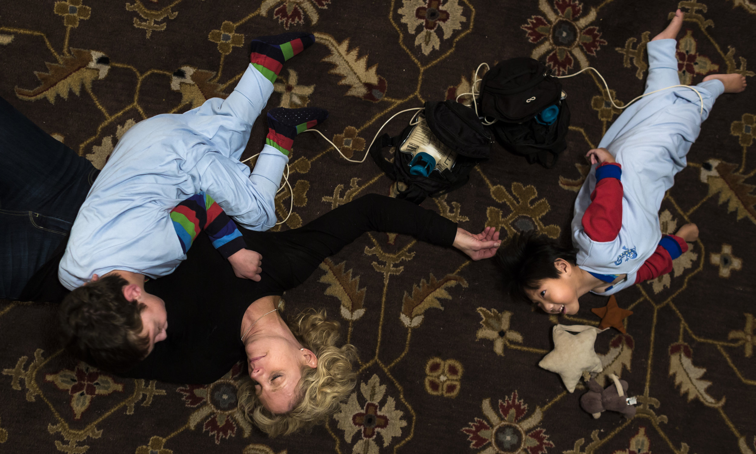  Brittany lays on her living room floor with her adopted sons Weston (7) and Graham (3). Both are being fed formula via a pump connected to their G-tubes. Nov. 18, 2017 