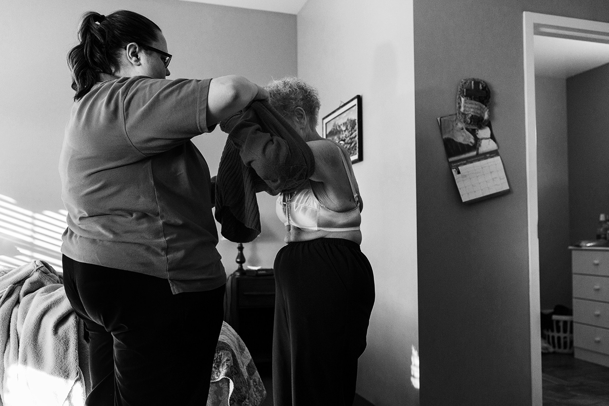 One of the memory-care facility employees assists Eloise in getting dressed. She was, at first, unhappy with her and Ward's move into the memory-care facility. Now, she and her husband rely on either her personal caretaker or the facility's employees to help them with many daily tasks.