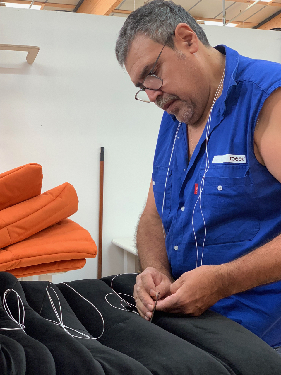 An upholsterer with more than 20 yrs. of experience hand-tufts a velvet Togo