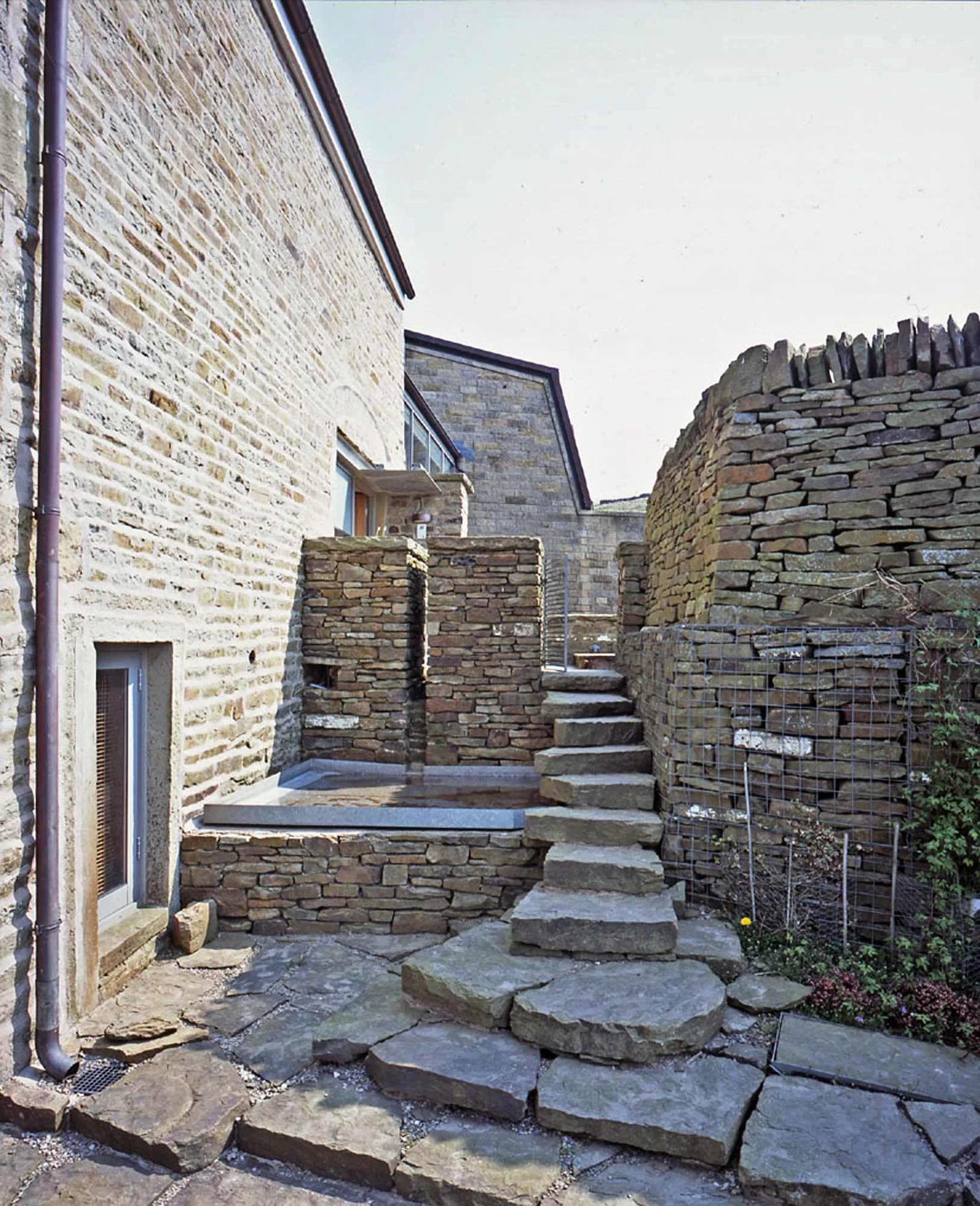 Cascading rooflines and landscaped stone courtyard view at Cotes Farm in Lancashire