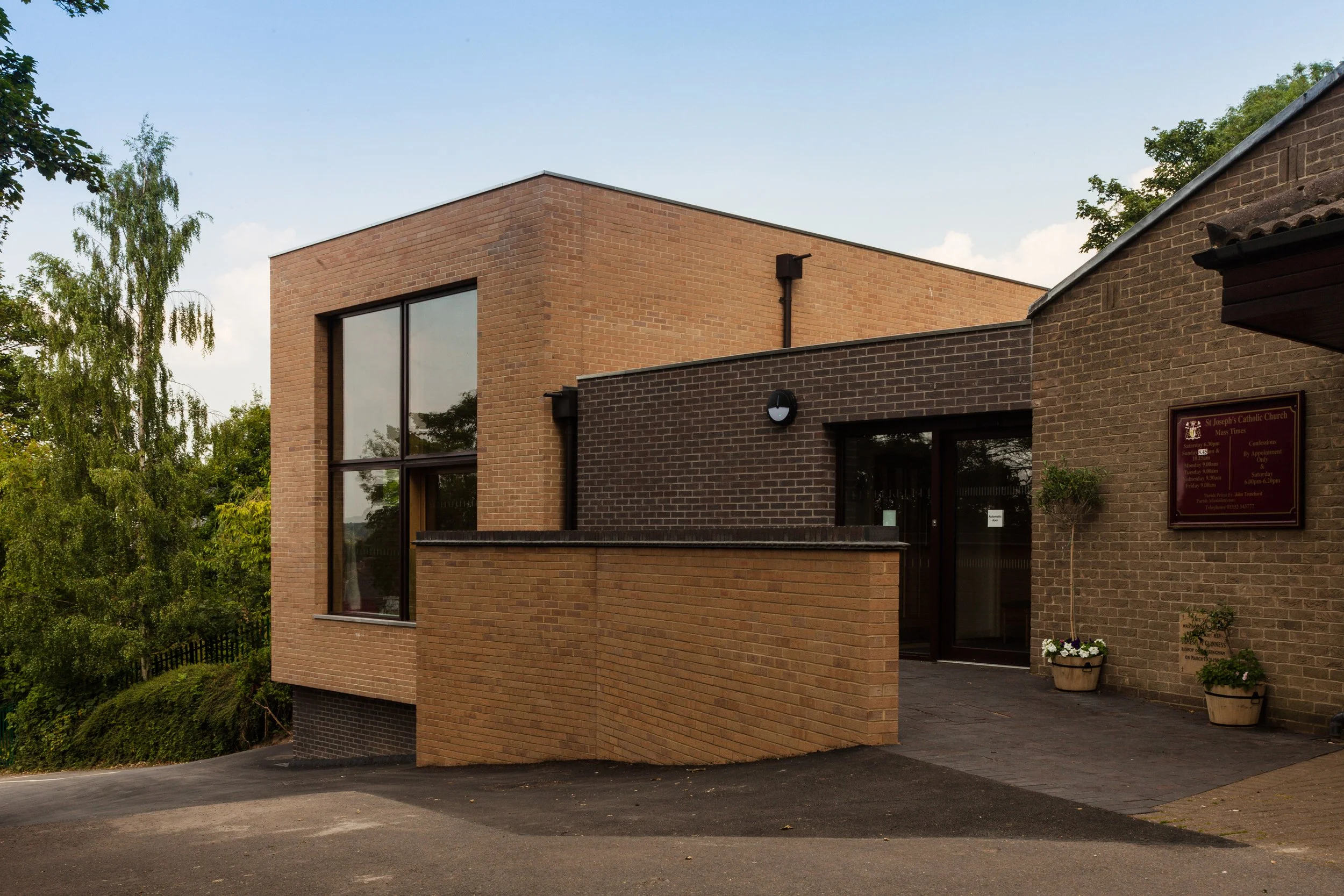 Close-up of modern brickwork detailing and blue brindle plinth at St Josephs Church Hall entrance.