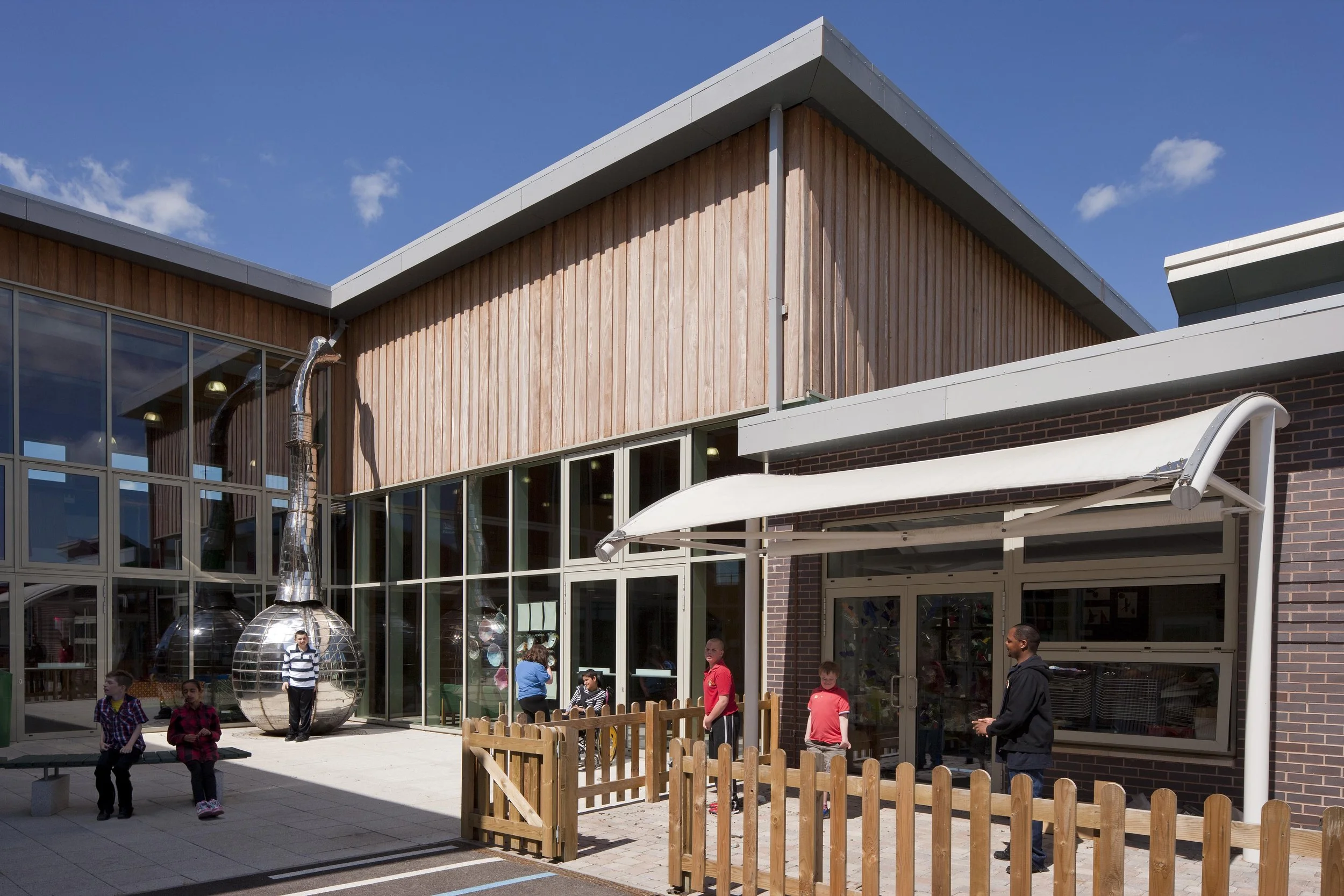 Exterior view of Oak Field School Nottingham showing warm timber cladding, brickwork, and the welcoming entrance forecourt.