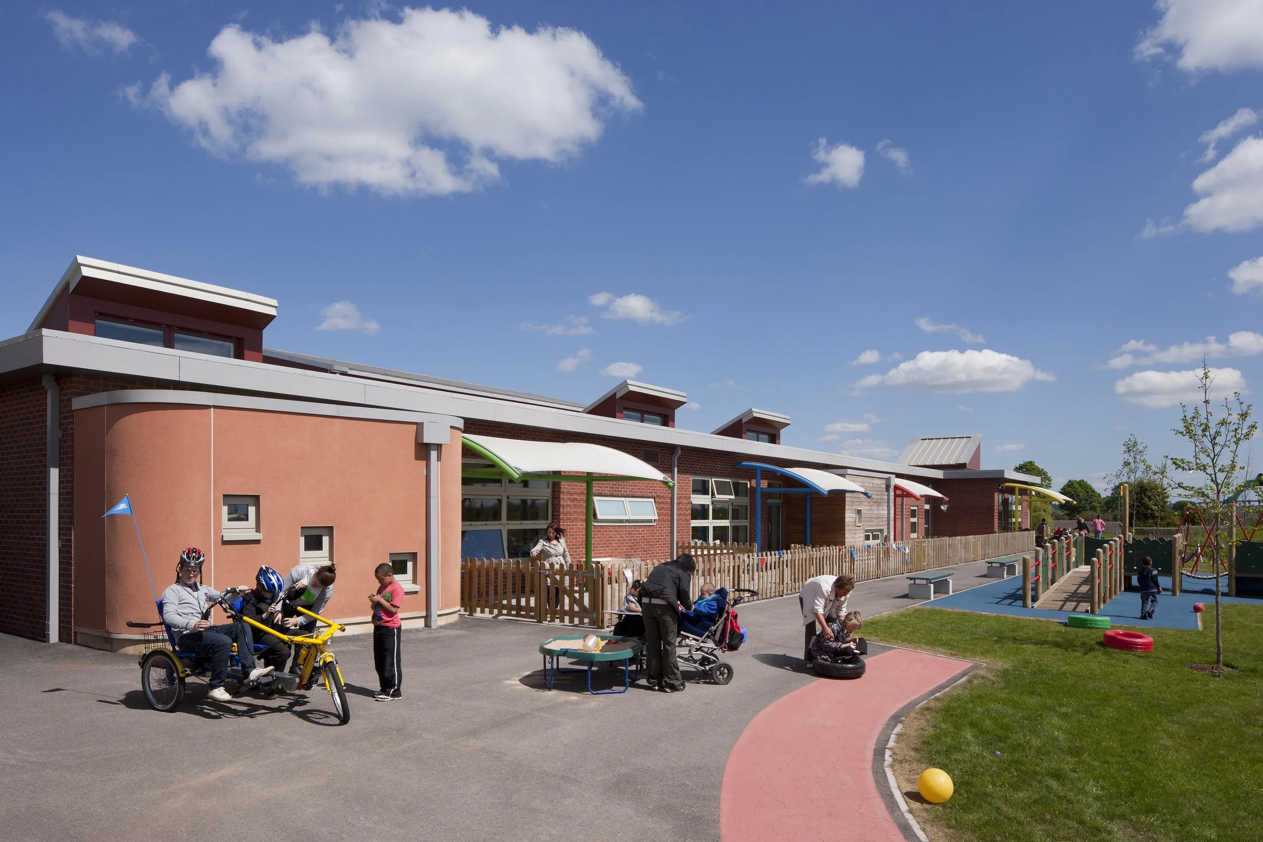 Curved brick facade of Oak Field School featuring large energy-efficient windows and timber louvres.