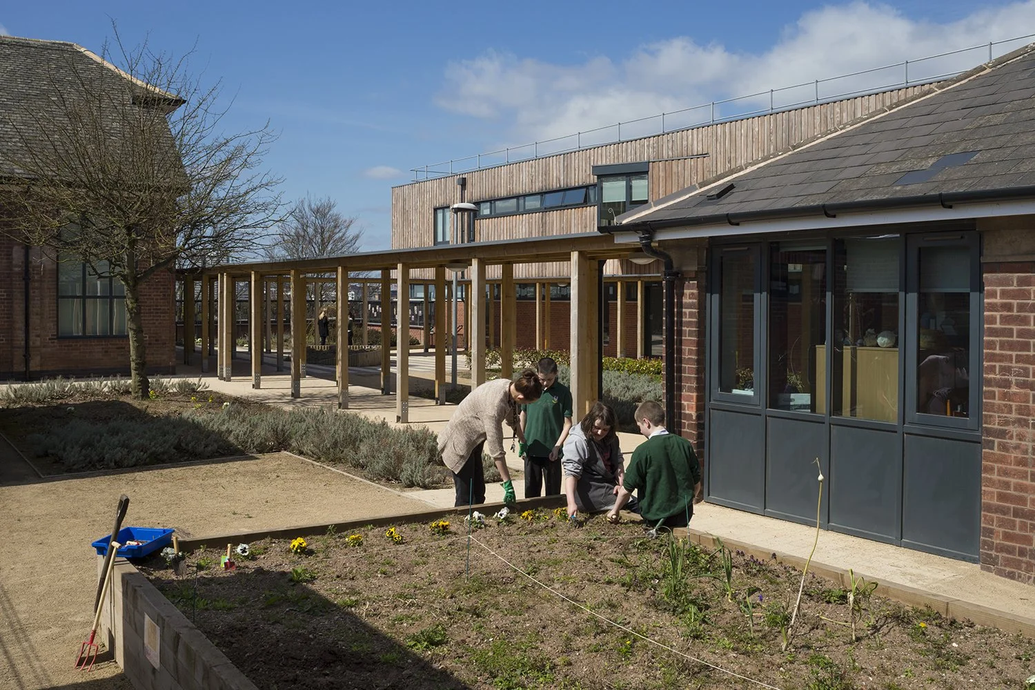 Landscaped courtyard and accessible stepped terrace at Rosehill School surrounded by refurbished 1930s brick buildings and mature trees.