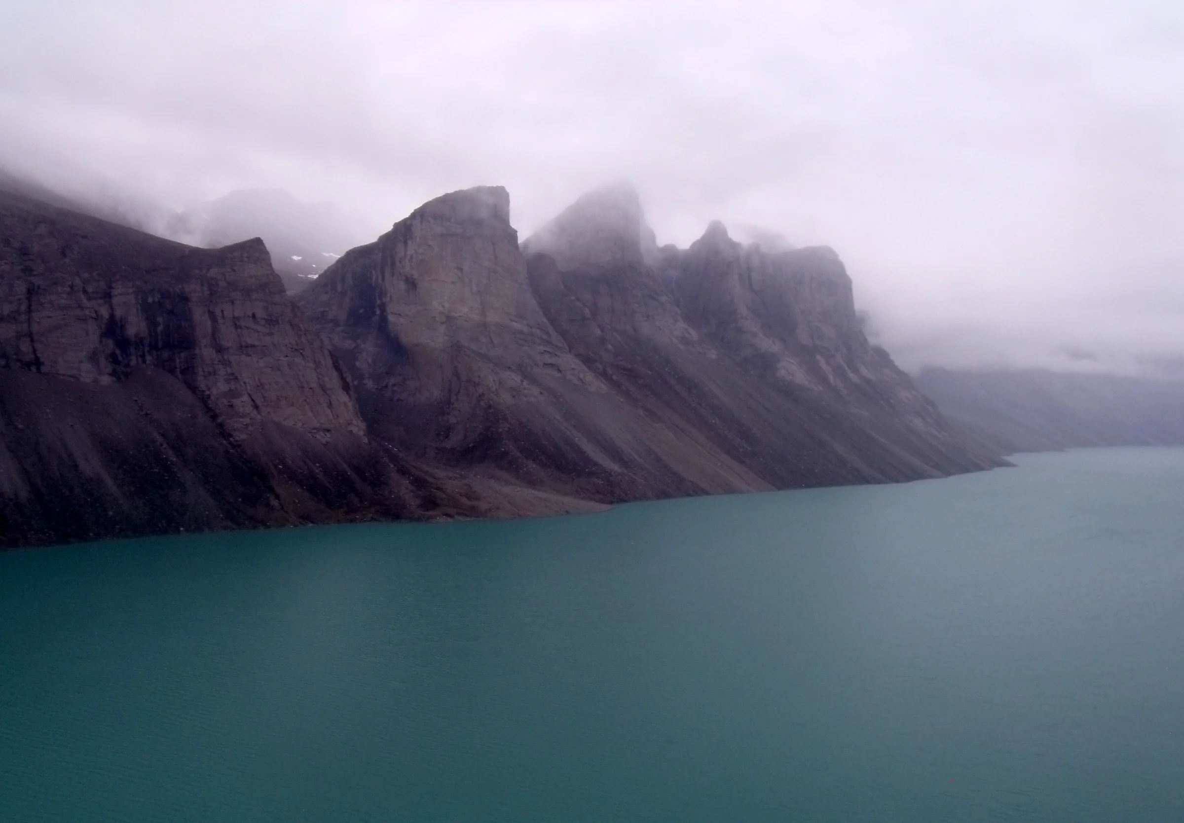 Land-locked freshwater fiord in northern Baffin Island, Nunavut with mile high teeth in the fog. Taken across Ayr Lake from a helicopter returning through the 'back door' to the hamlet of Clyde River. Photo by Mike Beauregard 