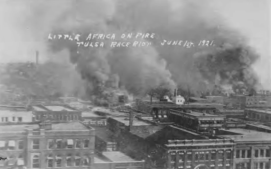 Little Africa on Fire. Tulsa Race Riot, June 1, 1921. Taken from roof of Hotel Tulsa on 3rd St. bt. Boston and Cincinnati Avenues. The first row of buildings is along 2nd Street. Smoke cloud on left is where the fire started (Cincinnati Ave. and the Frisco Tracks). This image is from a postcard in the collection of McFarlin Library, University of Tulsa