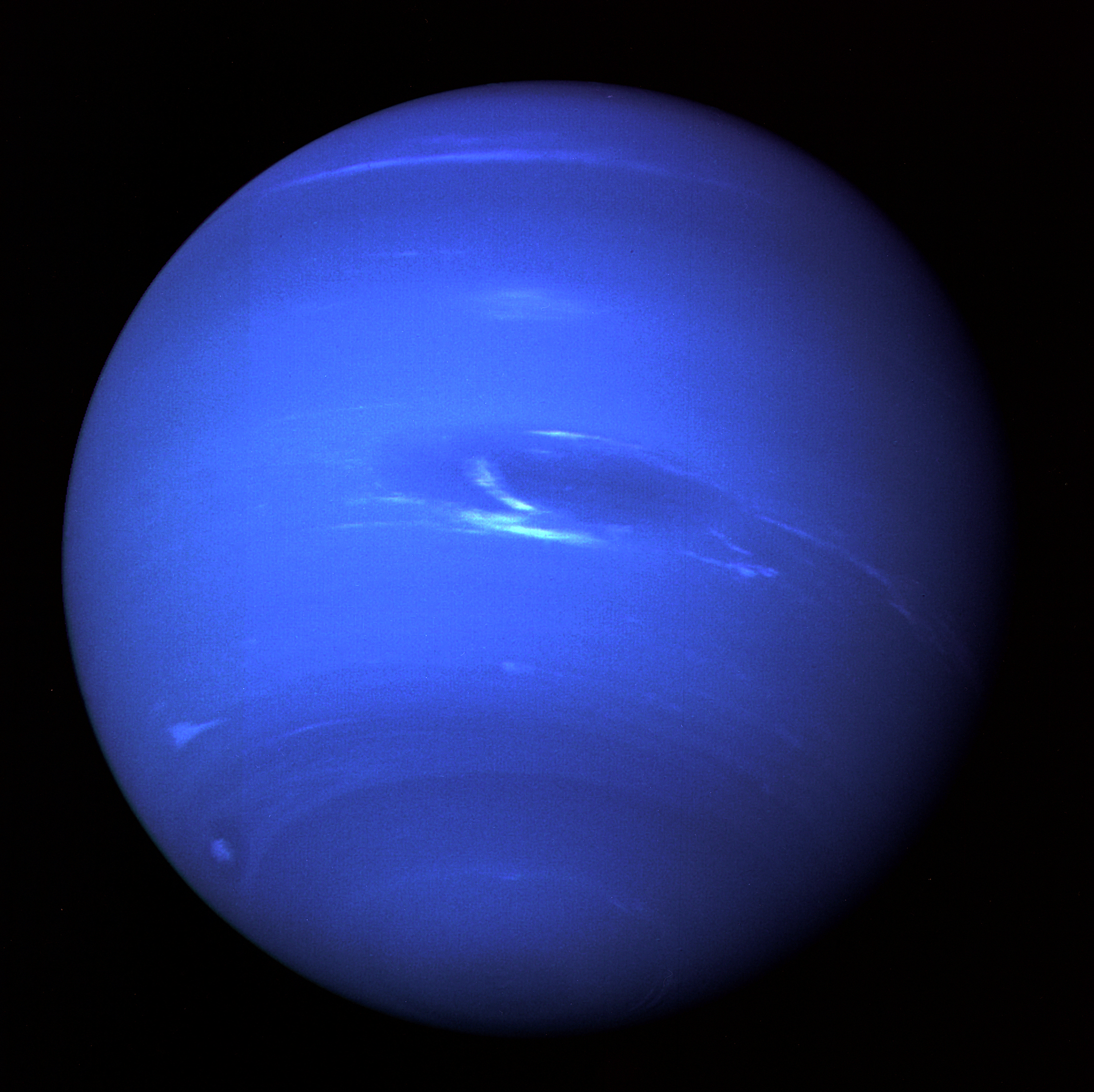 NASA’s Voyager 2 spacecraft gave humanity its first glimpse of Neptune and its moon Triton in the summer of 1989. This picture of Neptune was produced from the last whole planet images taken through the green and orange filters on the Voyager 2 narrow angle camera. The images were taken on Aug. 20, 1989, at a range of 4.4 million miles from the planet, 4 days and 20 hours before closest approach on Aug. 25. The picture shows the Great Dark Spot and its companion bright smudge; on the west limb the fast moving bright feature called “Scooter” and the little dark spot are visible. These clouds were seen to persist for as long as Voyager’s cameras could resolve them. North of these, a bright cloud band similar to the south polar streak may be seen. Image Credit: NASA