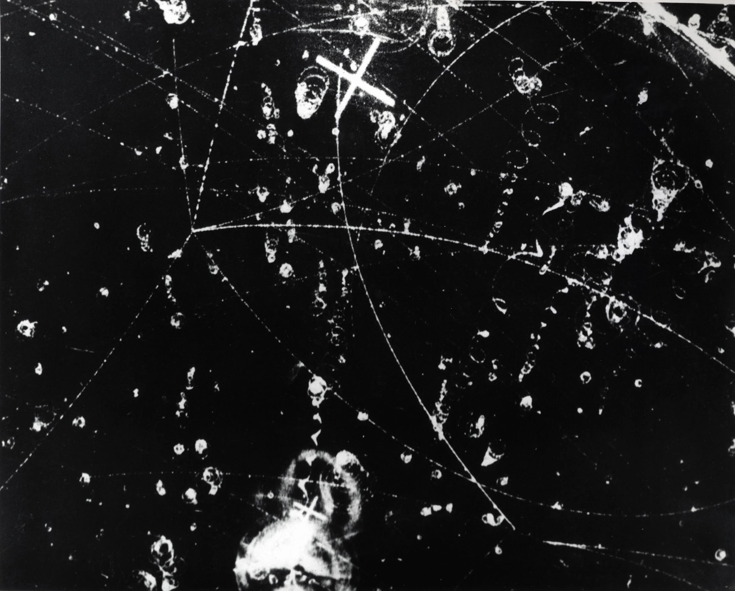 Nuclear particle tracks in the ten-inch bubble chamber mounted inside a superconducting magnet at Argonne show what happened to two negative K mesons that entered the bubble chamber from Argonne's ZGS. c.1966 Image credit: US Department of Energy, public domain