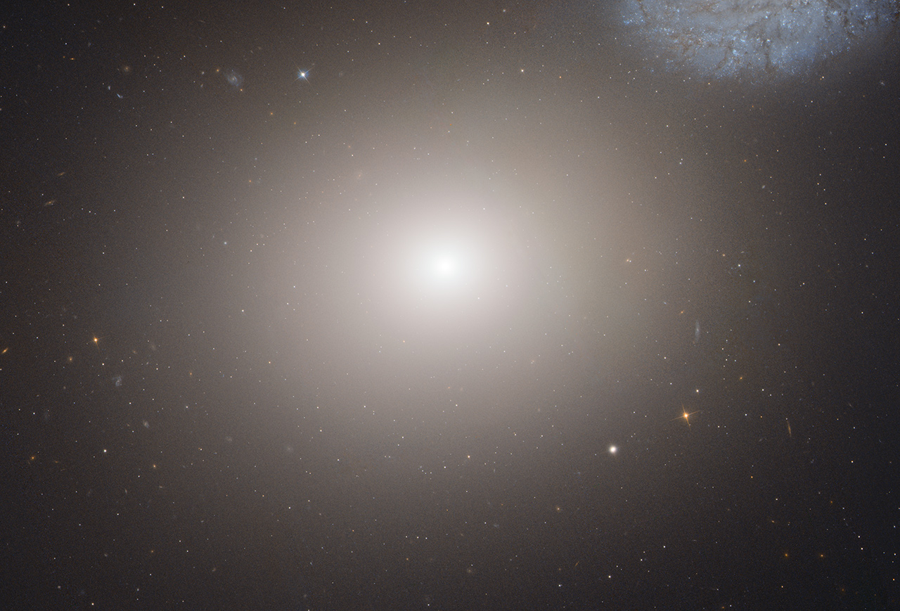 This is a Hubble Space Telescope image of the massive elliptical galaxy M60. The galaxy lies about 50 million light-years away inside the immense Virgo Cluster of 2,500 galaxies. A portion of the faint bluish spiral galaxy NGC 4647 can be seen in the upper right corner of this image. Image Credit: NASA, ESA, and the Hubble Heritage (STScI/AURA)-ESA/Hubble Collaboration