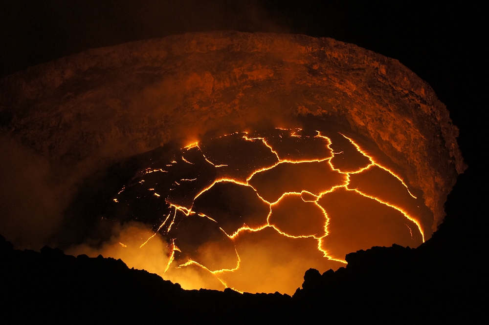 The active lava lake, Halema'uma'u crater, in Kilauea, Hawaii. Cracks in the cooler surface lava glow yellow from the heat of the molten rock. Image credit: Ivan Vtorov, CC-3.0 A-SA