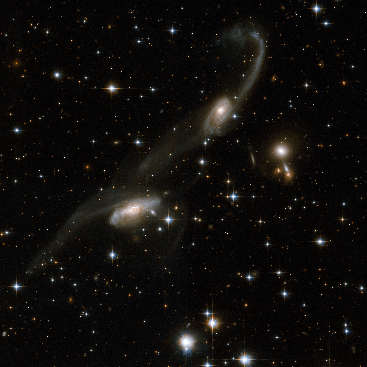 The galaxies of this beautiful interacting pair bear some resemblance to musical notes on a stave. Long tidal tails sweep out from the two galaxies: gas and stars were stripped out and torn away from the outer regions of the galaxies. The presence of these tails is the unique signature of an interaction. ESO 69-6 is located in the constellation of Triangulum Australe, the Southern Triangle, about 650 million light-years away from Earth. Credit: NASA, ESA, the Hubble Heritage (STScI/AURA)-ESA/Hubble Collaboration, and A. Evans (University of Virginia, Charlottesville/NRAO/Stony Brook University)