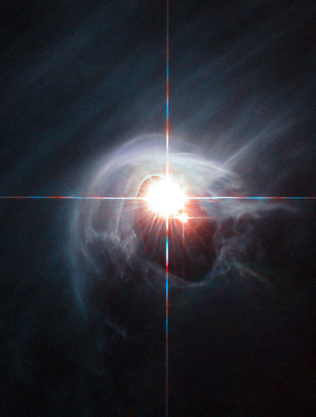 Two stars shine through the center of a ring of cascading dust in this image taken by the NASA/ESA Hubble Space Telescope. The star system is named DI Cha, and while only two stars are apparent, it is actually a quadruple system containing two sets of binary stars. As this is a relatively young star system it is surrounded by dust. The young stars are molding the dust into a wispy wrap. The host of this alluring interaction between dust and star is the Chamaeleon I dark cloud — one of three such clouds that comprise a large star-forming region known as the Chamaeleon Complex. DI Cha's juvenility is not remarkable within this region. In fact, the entire system is among not only the youngest but also the closest collections of newly formed stars to be found and so provides an ideal target for studies of star formation. Image credit: ESA/Hubble & NASA, Acknowledgement: Judy Schmidt
