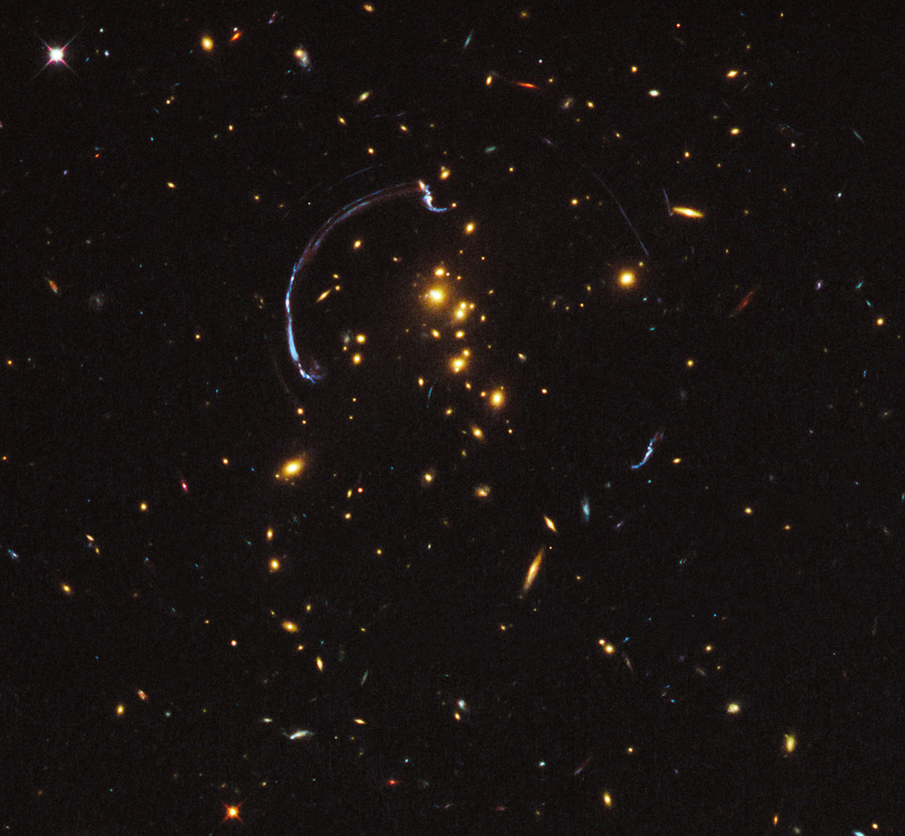 In this image the light from a distant galaxy, nearly 10 billion light-years away, has been warped into a nearly 90-degree arc of light in the galaxy cluster RCS2 032727-132623. The galaxy cluster lies 5 billion light-years away.Image credit: NASA; ESA; J. Rigby (NASA Goddard Space Flight Center); and K. Sharon (Kavli Institute for Cosmological Physics, University of Chicago)
