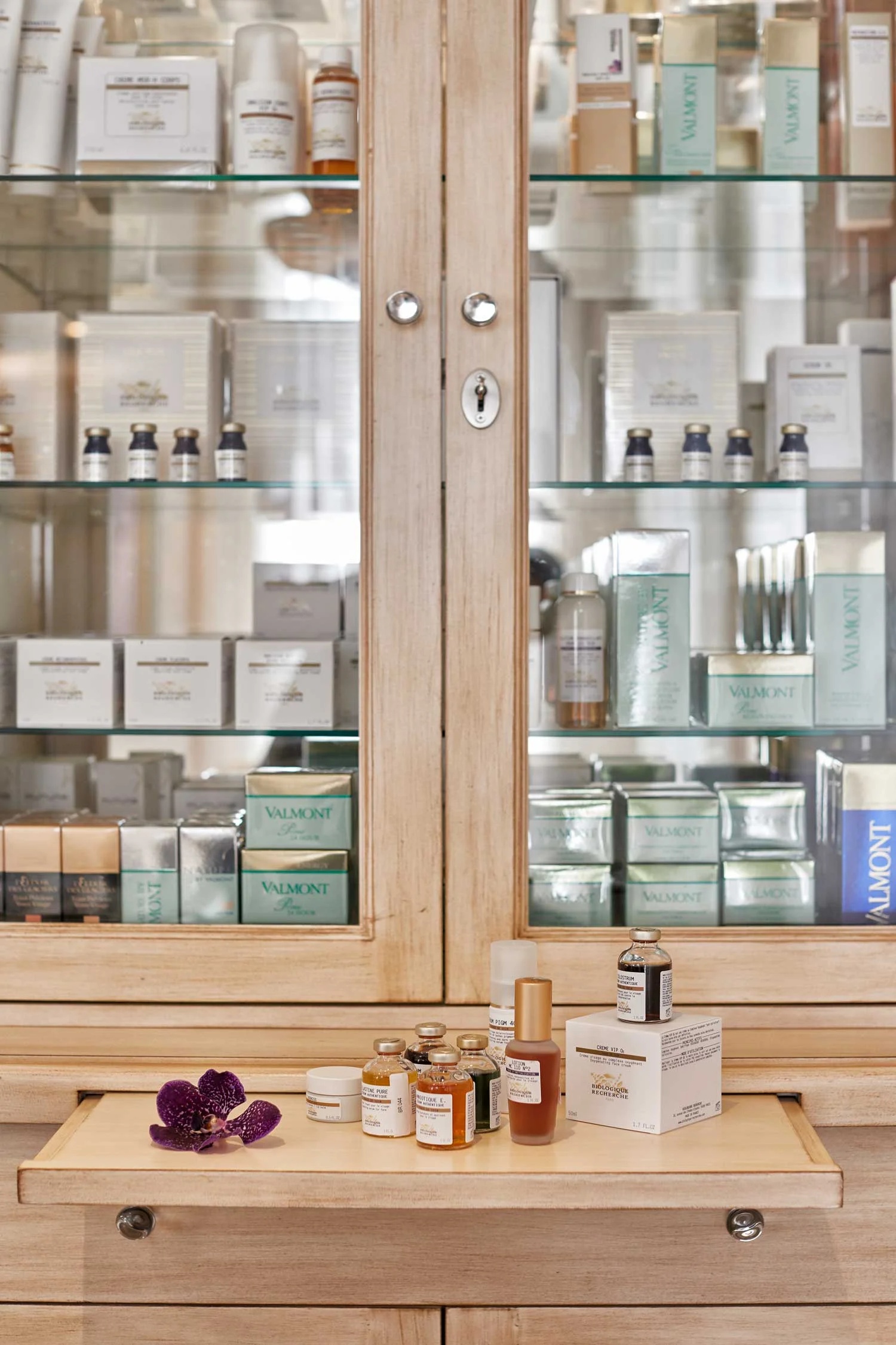 Customizing a space for a business or residence often requires the design of furniture, cabinetry, lighting and any number of features which comprise the interior. Here our client required a custom cabinet for product display, a reception desk, cabinetry throughout the treatment rooms, a bathroom vanity, and a kitchenette for employees. Form and function coexist; and we modulate our aesthetic according to our purpose. For example, the cabinetry for the treatment rooms was designed with a modern utilitarianism and visually discrete to recede into the background. In contrast, the reception area evokes the feel of a swanky Parisian salon at once haughty and homey with a residential vibe to the furnishings.