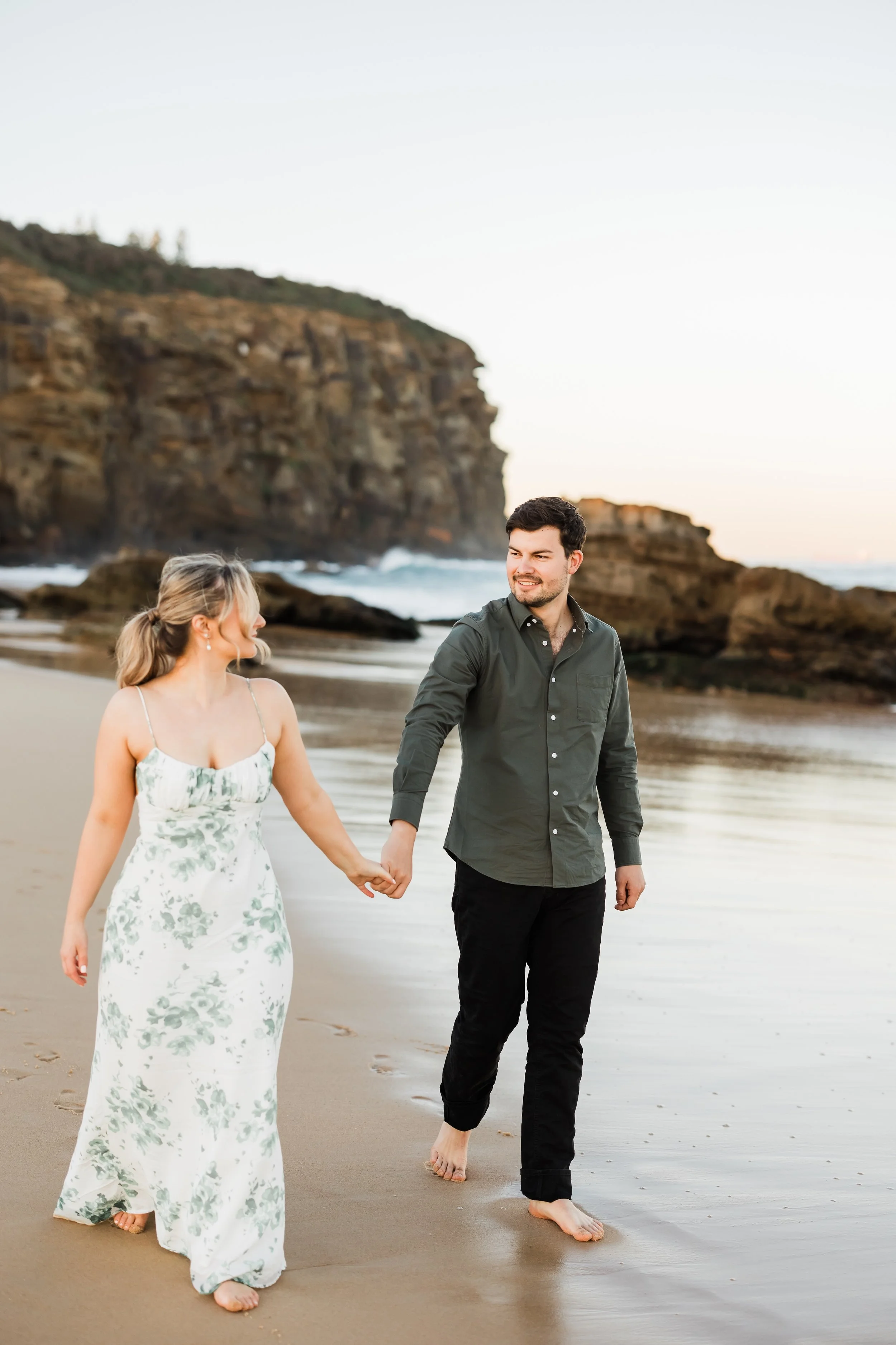 Couple walking along beach at sunset