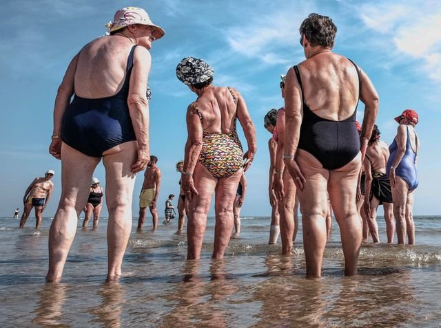 Group of older people in their swim wear with their feet in the ocean