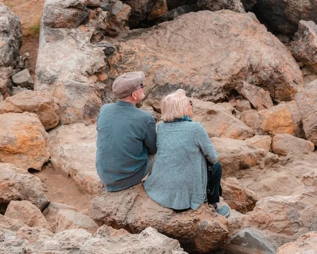 Retired couple sitting on the rocks looking out to sea