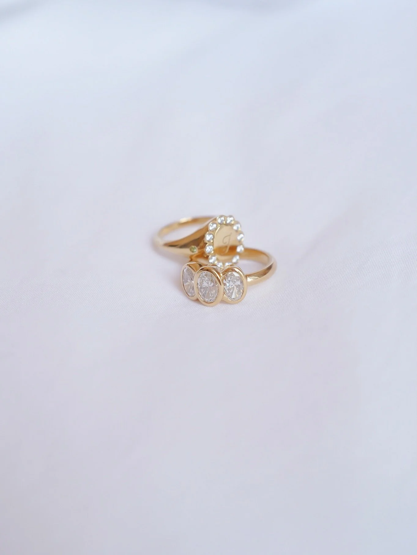 An engagement ring and a wedding ring that were never meant to match &mdash; and are so much better for it ✨

A personalised diamond halo signet alongside a three-stone oval diamond band, both crafted in 18ct Fairmined Gold and set with stunning Cana