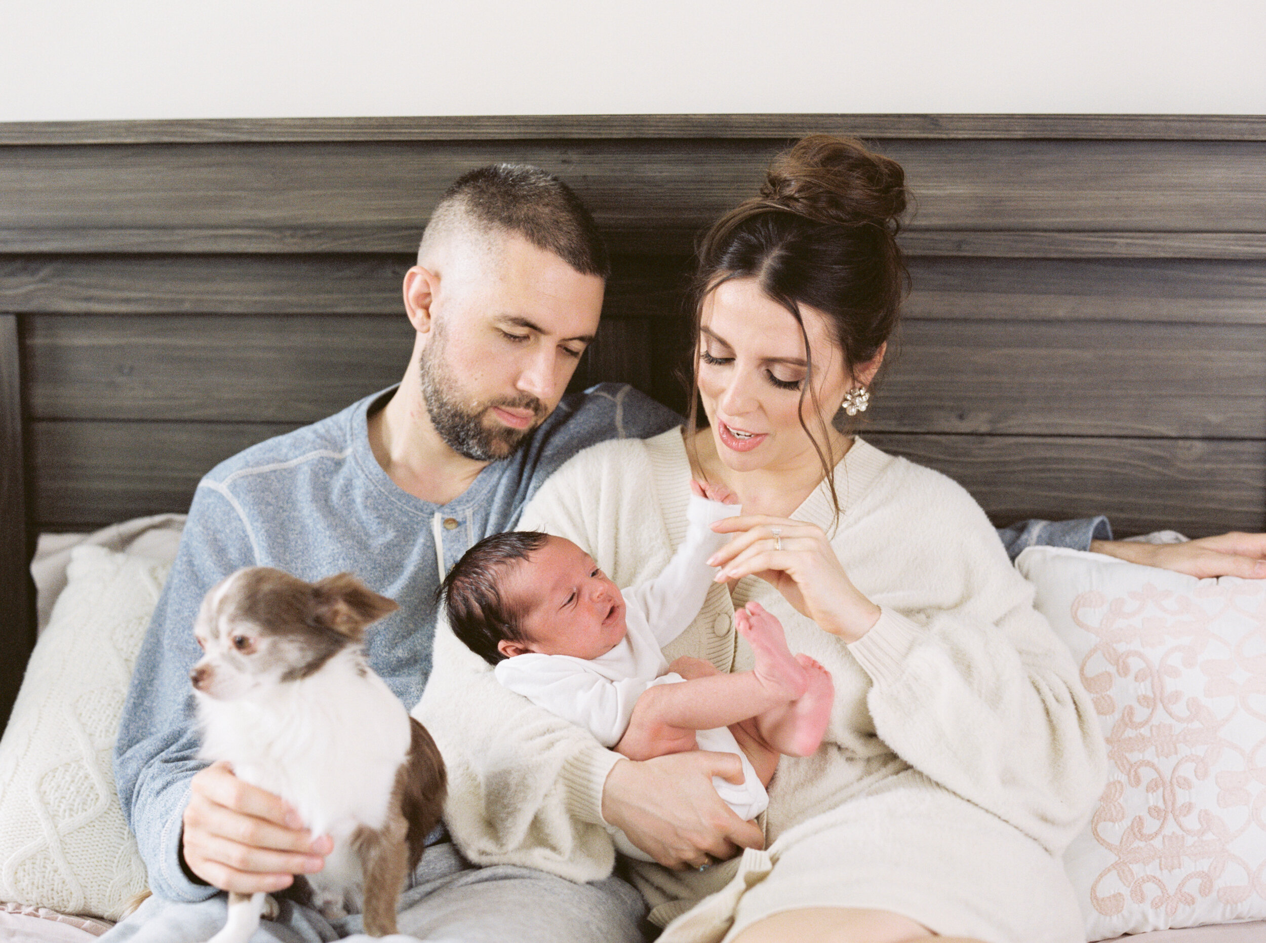 Mom and dad hold newborn baby with family dog 
