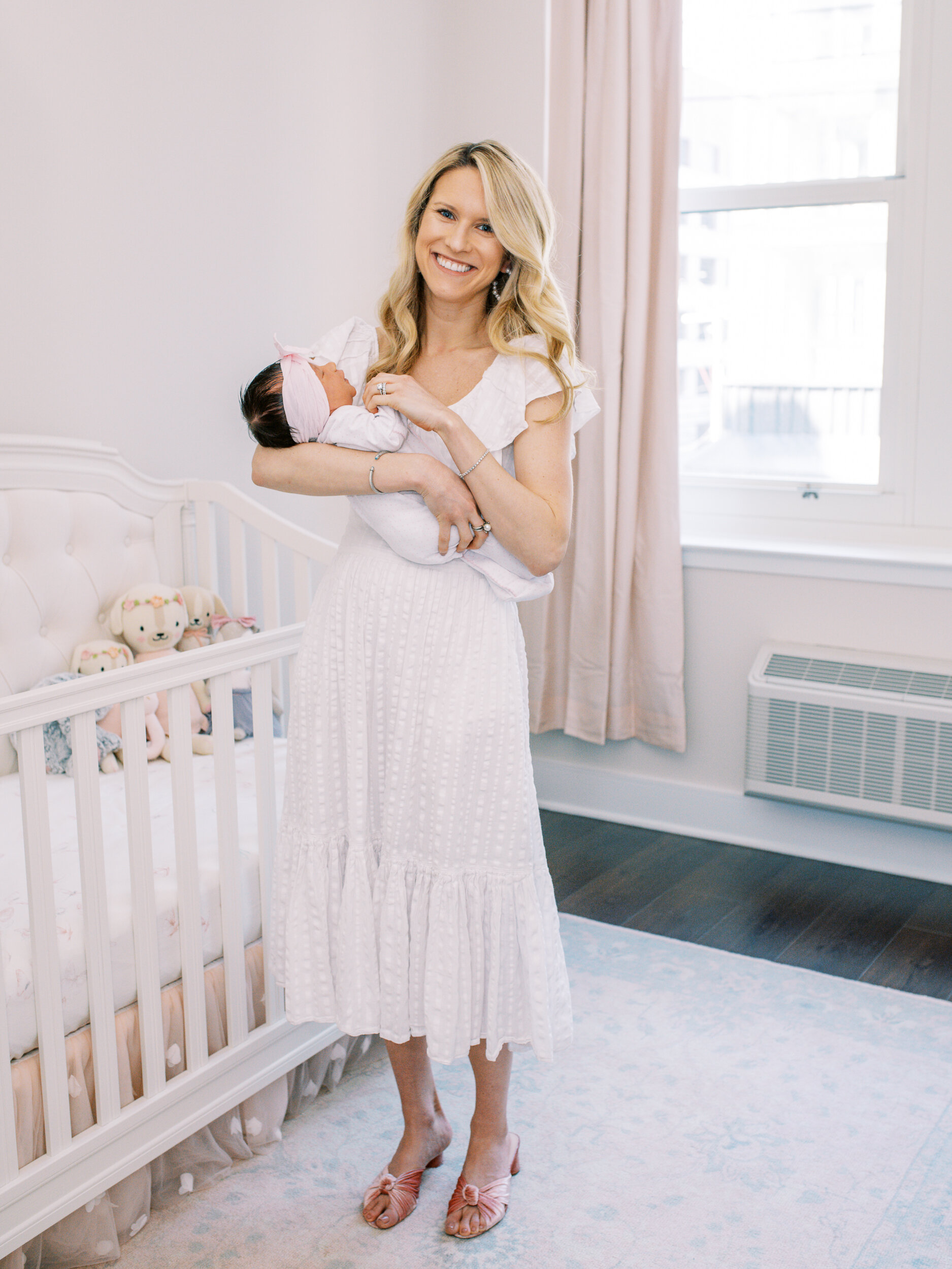 Mother holds baby girl in nursery during newborn shoot