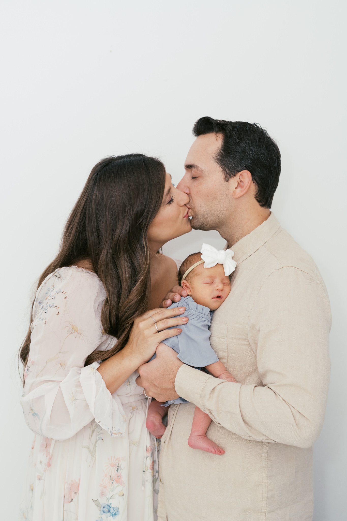 New Parents Kissing while holding new baby Girl during newborn photos